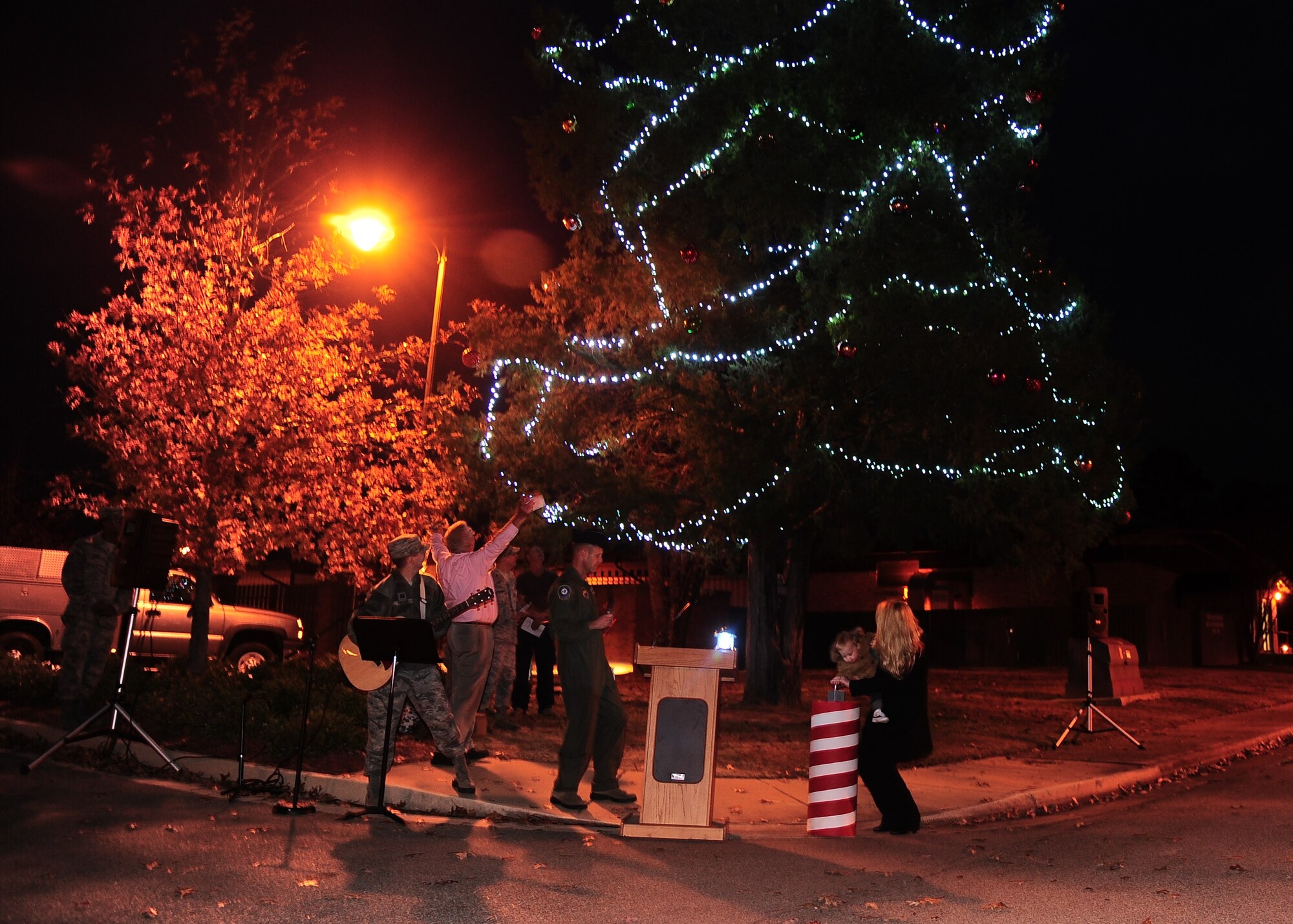 Representing the families of the deployed service members, Christina and Bryce Beddies, wife and son of deployed Air Force Tech Sgt. Douglas Beddies, 14th Operations Support Squadron, hit the switch to illuminate the tree outside of the
Mission Support Group building at the Christmas Tree Lighting ceremony put on by the Base Chapel Dec. 6.