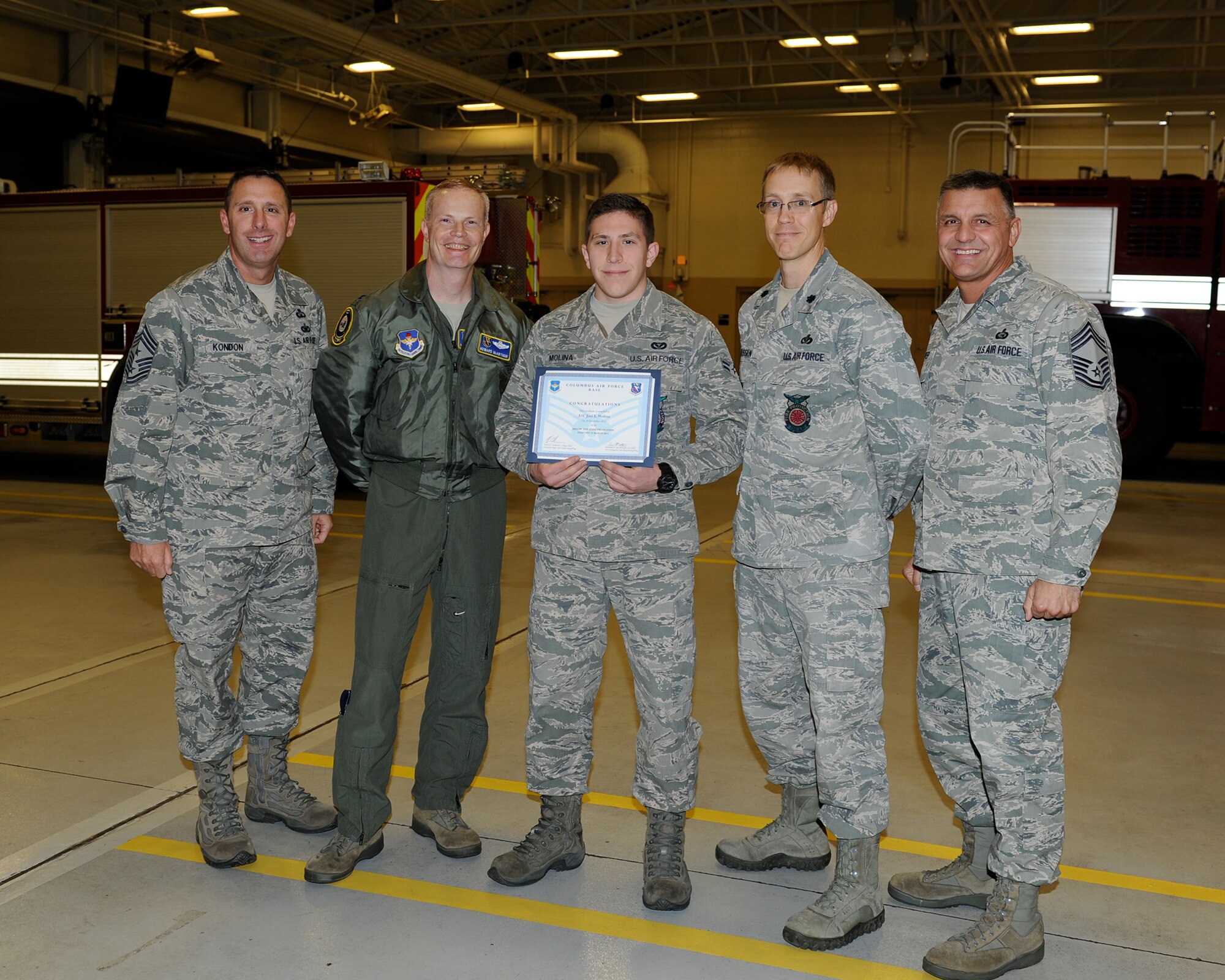 Chief Master Sgt. Vance Kondon, 14th Flying Training Wing Command Chief, Col. Howard McArthur, 14th Flying Training Wing Vice Commander, Col. David Meissen, 14th Civil Engineer Squadron Commander, and Chief Master Sgt. Peter Speen, 14th Mission Support Group Superintendent,  pose for a photo with Airman 1st Class Joel Molina, 14th Civil Engineer Squadron, who was awarded Senior Airman Below the Zone Dec. 11 at the Fire Department.