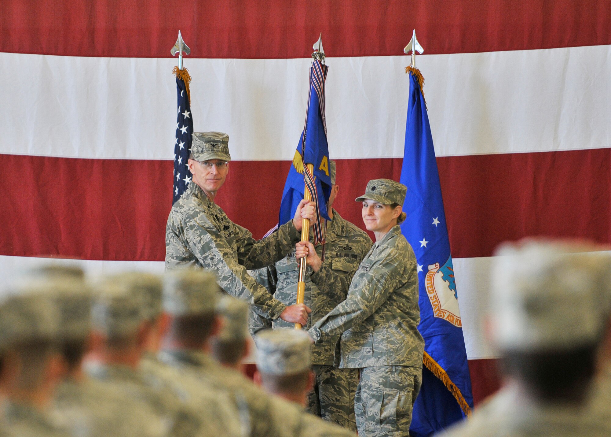 Colonel Curtis Hafer (Left), 325th Maintenance Group commander, passes the 325th Aircraft Maintenance Squadron guidon to Lt. Col. Charity Banks (Right) during a 325th AMXS assumption of command ceremony Dec 19 at Hangar 2. The 325th AMXS provides fully qualified F-22 Raptor crew chiefs for worldwide assignment, directing maintenance activities for the largest aircraft maintenance squadron in the Combat Air Force. (U.S. Air Force photo by Staff Sgt. Javier Cruz)