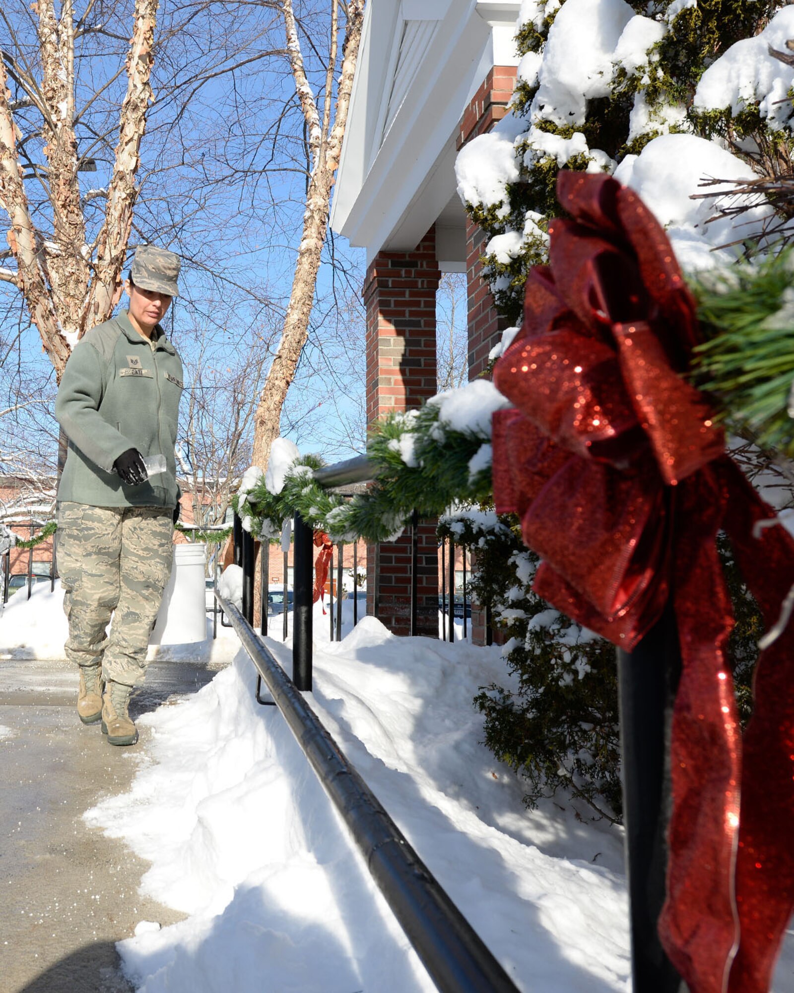 Staff Sgt. Jenny Cate, Chapel Program Support NCO in charge, spreads salt on the walkway at an entrance of the base chapel Dec. 18 after cleaning up from a snow storm that saw several inches on base. For a complete listing of Christmas services at the chapel Dec. 24 and Dec. 25, visit the Hanscom Air Force Base Chapel Facebook page. (U.S. Air Force photo by Mark Herlihy)
