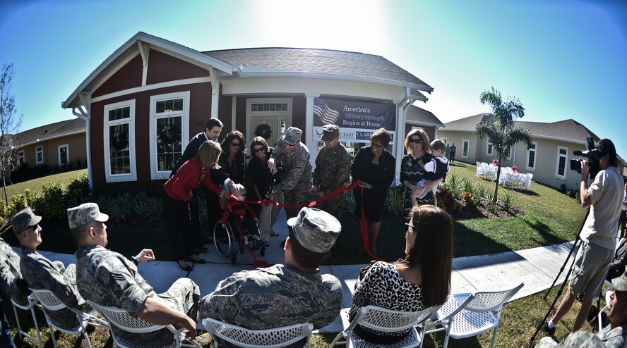 MacDill Air Force Base leadership along with members of Clark Realty Capital and new housing residents, cut the ribbon to one of the 10 newly constructed Americans with Disabilities Act homes, Dec. 18, 2013. The project was one of the collaborative efforts between MacDill and Clark Realty Capital, who have developed and constructed 327 new homes on 175 acres at the base for service members and their families. (U.S. Air Force photo by Staff Sgt. Brandon Shapiro/Released)