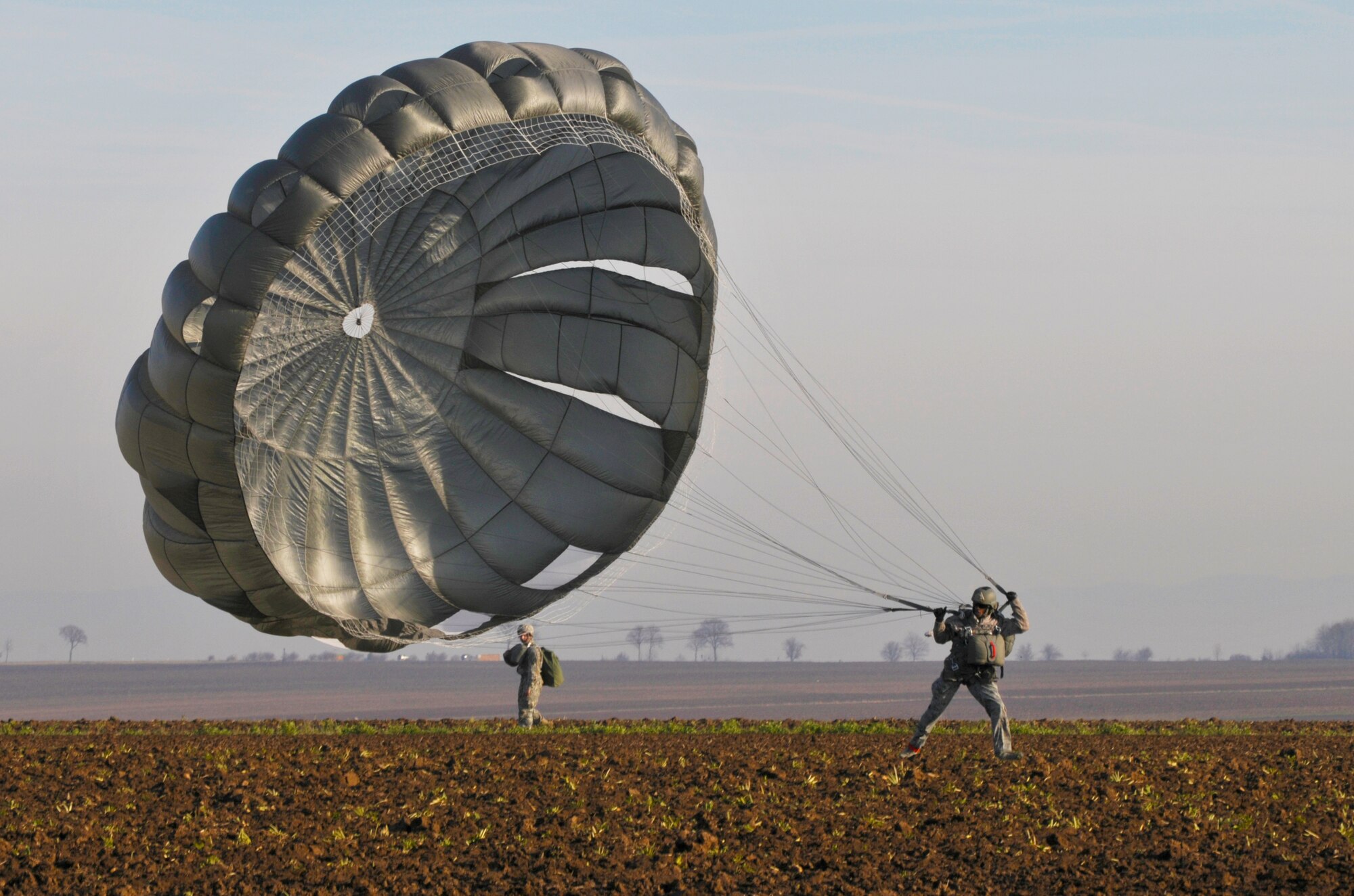 A paratrooper gets a hold of his parachute to pack it up after landing during International Jump Week, Dec. 17, 2013, Ramstein Air Base, Germany. . Jump Week is a chance for NATO countries and U.S. forces can build partnerships and train together. (U.S. Air Force photo/Senior Airman Jose Leon)