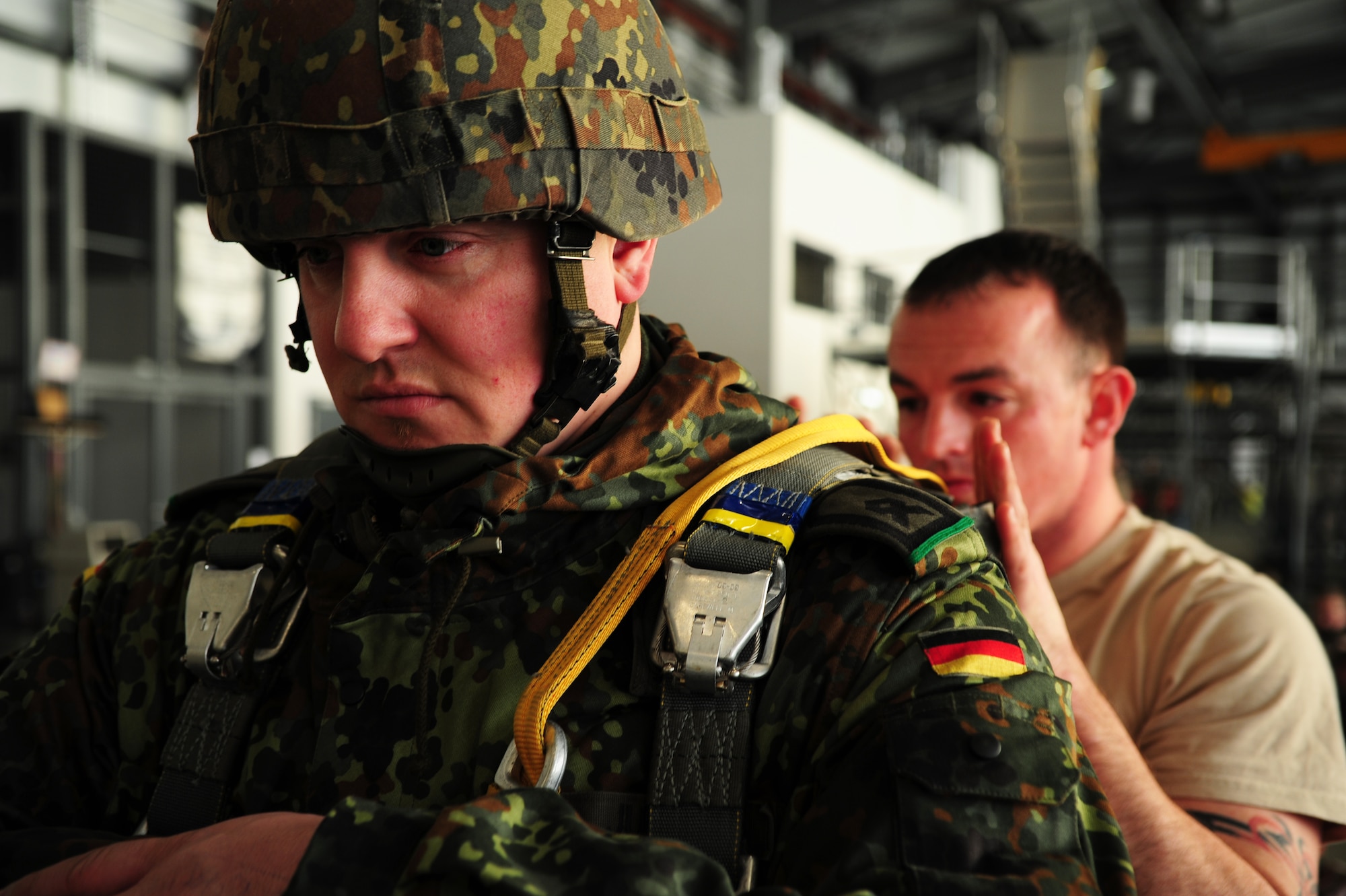 Army Sgt. 1st Class Brett Macy, Bravo 173 mortar platoon sergeant, checks the gear of German Master Sgt. Marcel Just, Airborne Battalion 313 air transport sergeant, with his parachute during International Jump Week, Dec. 17, 2013, Ramstein Air Base, Germany. International Jump Week started with a bang this year as Santa Claus joined service members from different branches of the U.S. along with NATO forces. (U.S. Air Force photo/Senior Airman Hailey Haux)