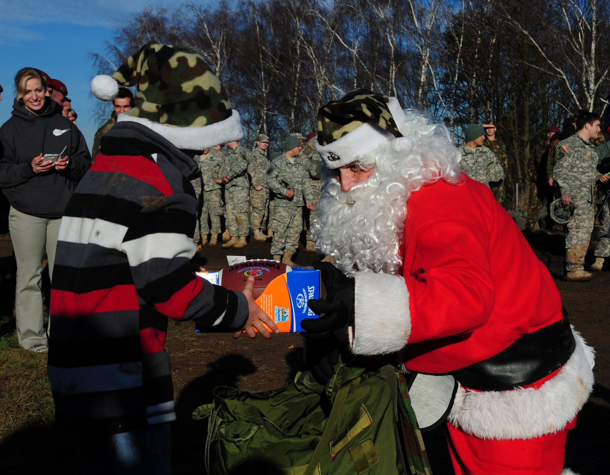 Santa Claus hands a football to a child during the toy drop, which initiated International Jump Week, Dec. 16, 2013. Having more than 200 paratroopers donated toys, leaving Santa with a lot of joy to deliver to the children. (U.S. Air Force photo/Senior Airman Hailey Haux)