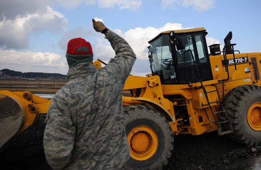 Master Sgt. William Webb, Detachment 1, 554 RED HORSE, signals to Staff Sgt. Souridet Thongrivong, 8th Civil Engineer Squadron, during an Airfield Damage Repair exercise at Kunsan Air Base, Republic of Korea, Dec. 19, 2013. Members from Detachment 1 554 RED HORSE came to Kunsan to train and develop civil engineer Airmen during the week long Silver Flag exercise. (U.S. Air Force photo by Senior Airman Armando A. Schwier-Morales/Released)