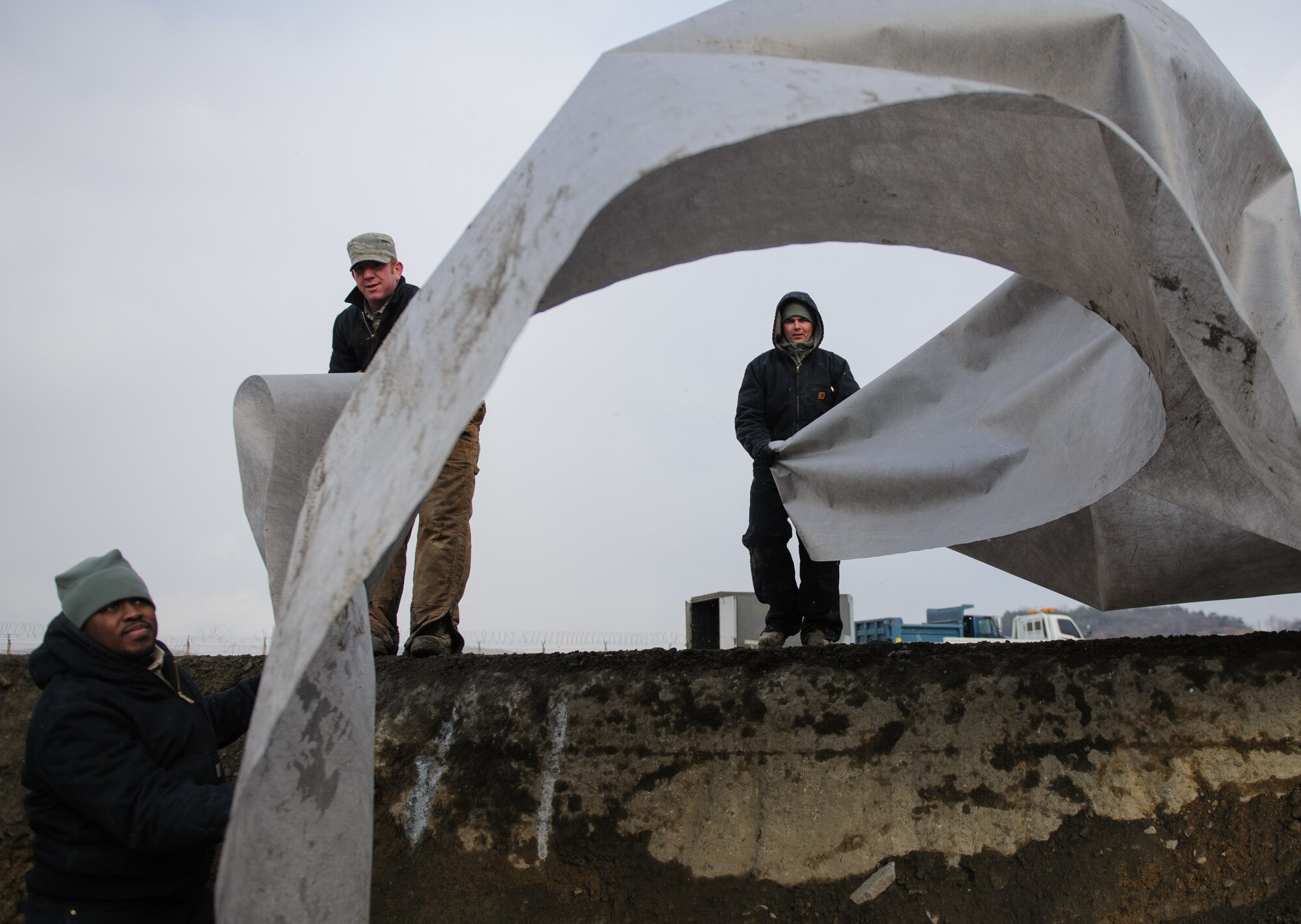 Senior Airman Garvin Karel, left, Staff Sgt. Kelby Plowman, middle, and Airman 1st Class Ryan O’Keefe, 8th Civil Engineer Squadron, right, place a tarp to begin filling a crater at Kunsan Air Base, Republic of Korea, Dec. 19, 2013. Members from Detachment 1 554 RED HORSE came to Kunsan to train and develop civil engineer Airmen during the week long Silver Flag exercise. (U.S. Air Force photo by Senior Airman Armando A. Schwier-Morales/Released)