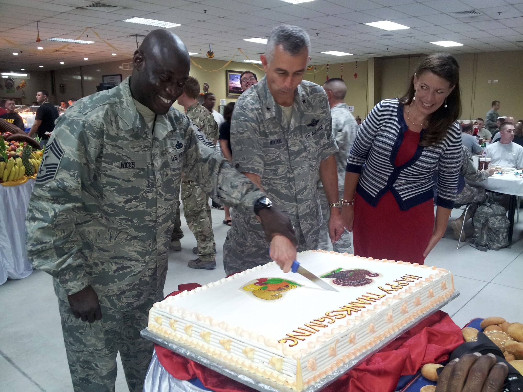 Chief Master Sgt. Roy Wicks, Brig. Gen. Roger H. Watkins and his wife Leslie cut a Thanksgiving Day cake at the 379th Air Expeditionary Wing in Southwest Asia, Nov. 28, 2013. Senior leadership volunteered throughout the day to serve meals to service members at the base dining facilities. Watkins is the 379th AEW commander and hails from Fort Worth, Texas, and Wicks is the 379th AEW command chief and hails from Kinston, N.C.  (U.S. Air Force photo/Courtesy photo)
