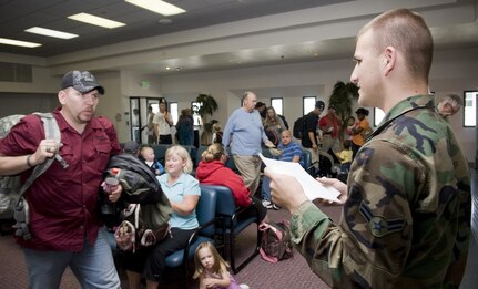 Airman 1st Class Wade Helms calls the names of travelers to board a bus that will take them to an awaiting C-5 Galaxy bound for Hickam Air Force Base, Hawaii, on April 17. The TSA is expanding expedited screening for military members.