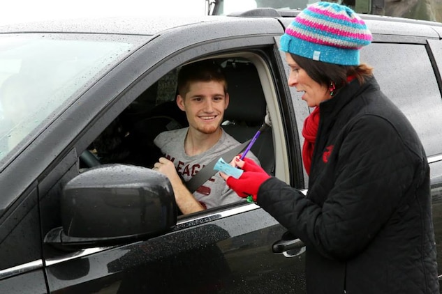 Kristyn Fleming gives Petty Officer 3rd Class Brice Courtnage a slip to redeem presents for him family during the Armed Services YMCA's Secret Santa Event Dec. 19. Fleming is an operations assistant with the ASYMCA. 

