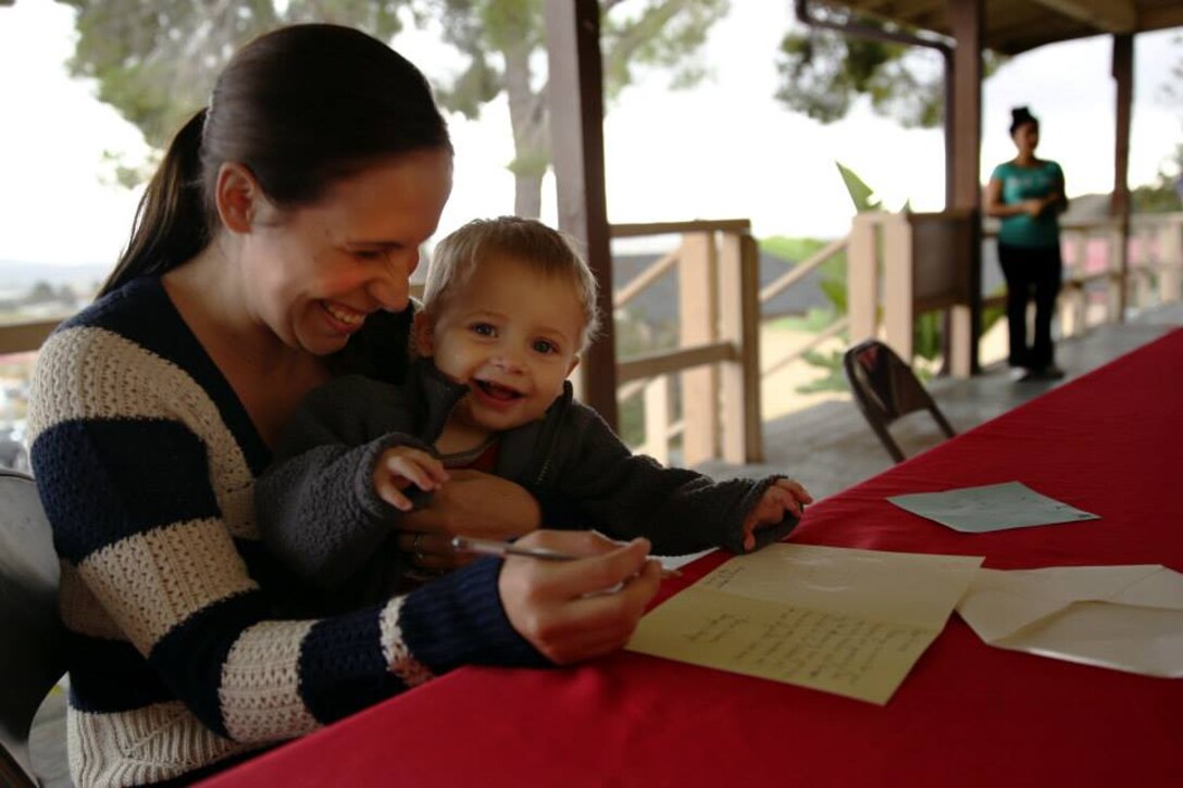 Victoria Courtnage and her son, Ben, write a thank you letter to the sponsors who donated gifts to her family during the Armed Services YMCA's Secret Santa Event Dec. 19. 