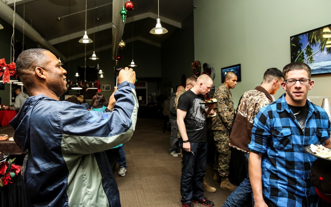 Sergeant Maj. John Scott, left, sergeant major, 15th Marine Expeditionary Unit, captures a moment during a holiday meal at the 21 Area Single Marine Program recreation center aboard Camp Pendleton, Calif., on Dec. 18. Single Marines were invited to enjoy a home cooked meal and celebrate the holidays among friends during an event hosted by the 21 area family readiness officers. (U.S. Marine Corps photo by Cpl. Emmanuel Ramos)