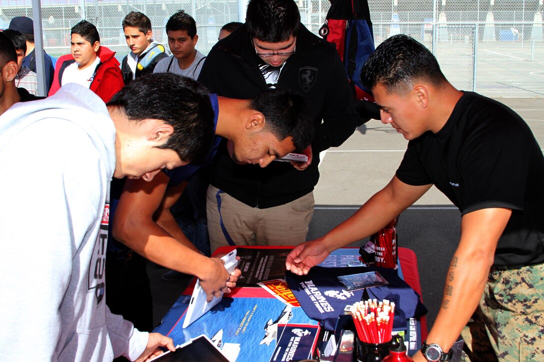 Staff Sgt. Pablo Rojas, right, a recruiter with Recruiting Sub Station National City, explains to students how to fill out the pull-up challenge application during the ASA 2013 High School Tour at Montgomery High School in San Diego, Dec. 5. Marines partnered with ASA Entertainment, a traveling actions sports demonstration team, to present a pull-up and flexed-arm hang challenge at various high schools Dec. 2 through 13.