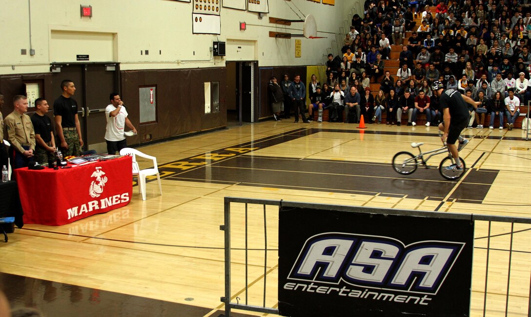 From left, Sgt. Christopher Murphy, Sgt. Eddie Quezada and Pfc. Ramsey Borja watch an action sports demonstration from a Marine Corps booth during the ASA 2013 High School Tour at Serra High School in San Diego, Dec. 6. Marine Corps Recruiting Station San Diego Marines partnered with ASA Entertainment for their tobacco free and anti-bullying campaign Dec. 2 through 13. While extreme sports performers spoke on healthy life style choices the recruiters tested students physical fitness levels with pull-up and flexed-arm hang challenges.