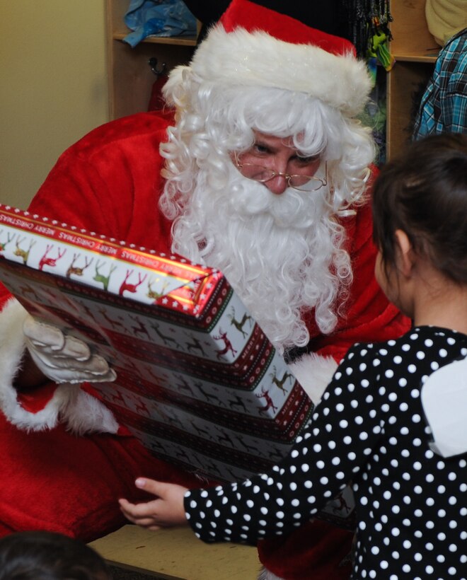 Santa Claus teamed up with more than 20 volunteers from Ellsworth Air Force Base, S.D., to distribute gifts to children enrolled in the Youth & Family Services Child Care program in Rapid City, S.D., Dec. 19, 2013. This is the seventh year the 28th Operations Group has conducted the Angel Tree program. (U.S. Air Force photo by Senior Airman Anania Tekurio/Released)
