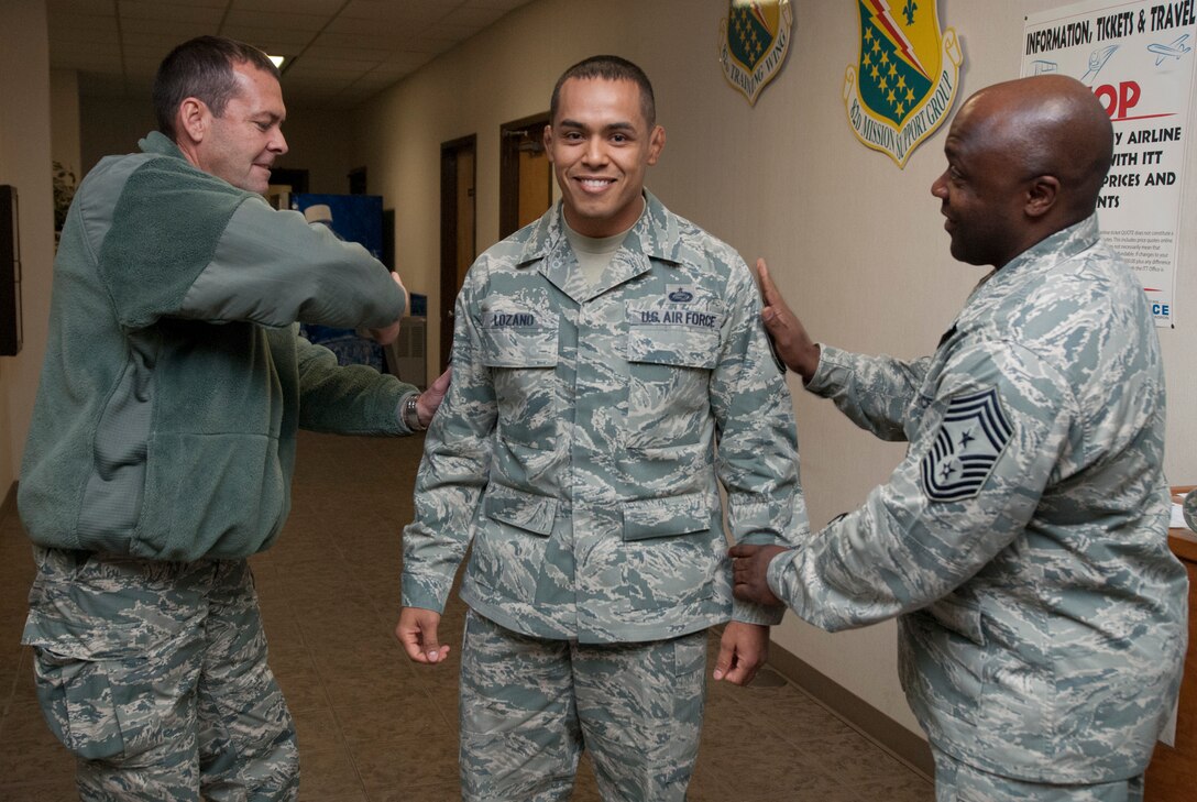 Brig. Gen. Scott Kindsvater, 82nd Training Wing commander, and Chief Master Sgt. Eric Johnson, pin master sergeant stripes on Tech. Sgt. Rolando Lozano during a Stripes For Exceptional Stripes during a surprise visit to the 82nd Force Support Squadron Dec. 20, 2013. Lozano was STEP promoted to master sergeant for his leadership as the 82nd Force Support Squadron student relocations NCOIC. His wife, Master Sgt. Nadia Lozano, was STEP promoted in July 2013. (U.S. Air Force photo/Tech. Sgt. Mike Meares)