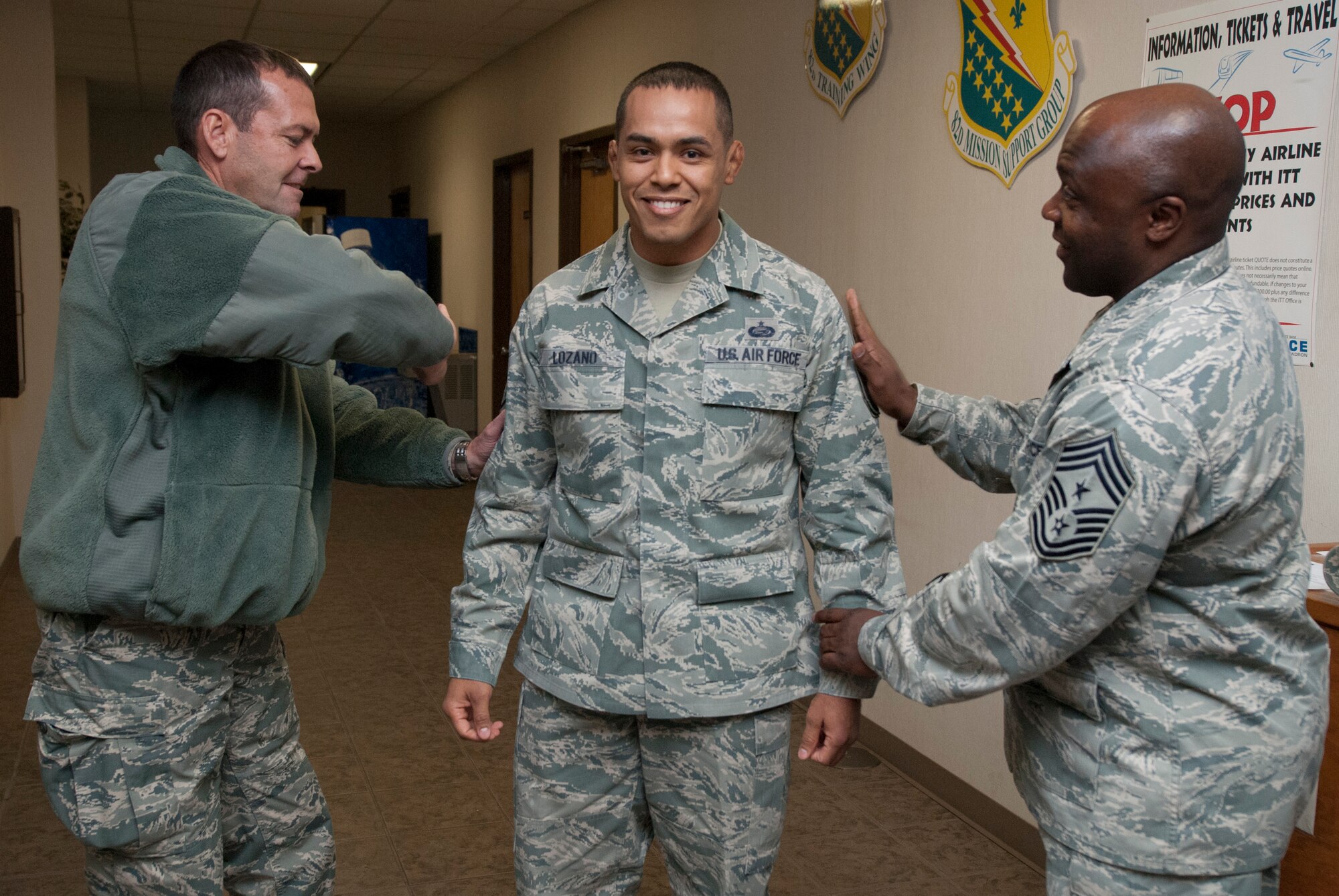 Brig. Gen. Scott Kindsvater, 82nd Training Wing commander, and Chief Master Sgt. Eric Johnson, pin master sergeant stripes on Tech. Sgt. Rolando Lozano during a Stripes For Exceptional Stripes during a surprise visit to the 82nd Force Support Squadron Dec. 20, 2013. Lozano was STEP promoted to master sergeant for his leadership as the 82nd Force Support Squadron student relocations NCOIC. His wife, Master Sgt. Nadia Lozano, was STEP promoted in July 2013. (U.S. Air Force photo/Tech. Sgt. Mike Meares)
