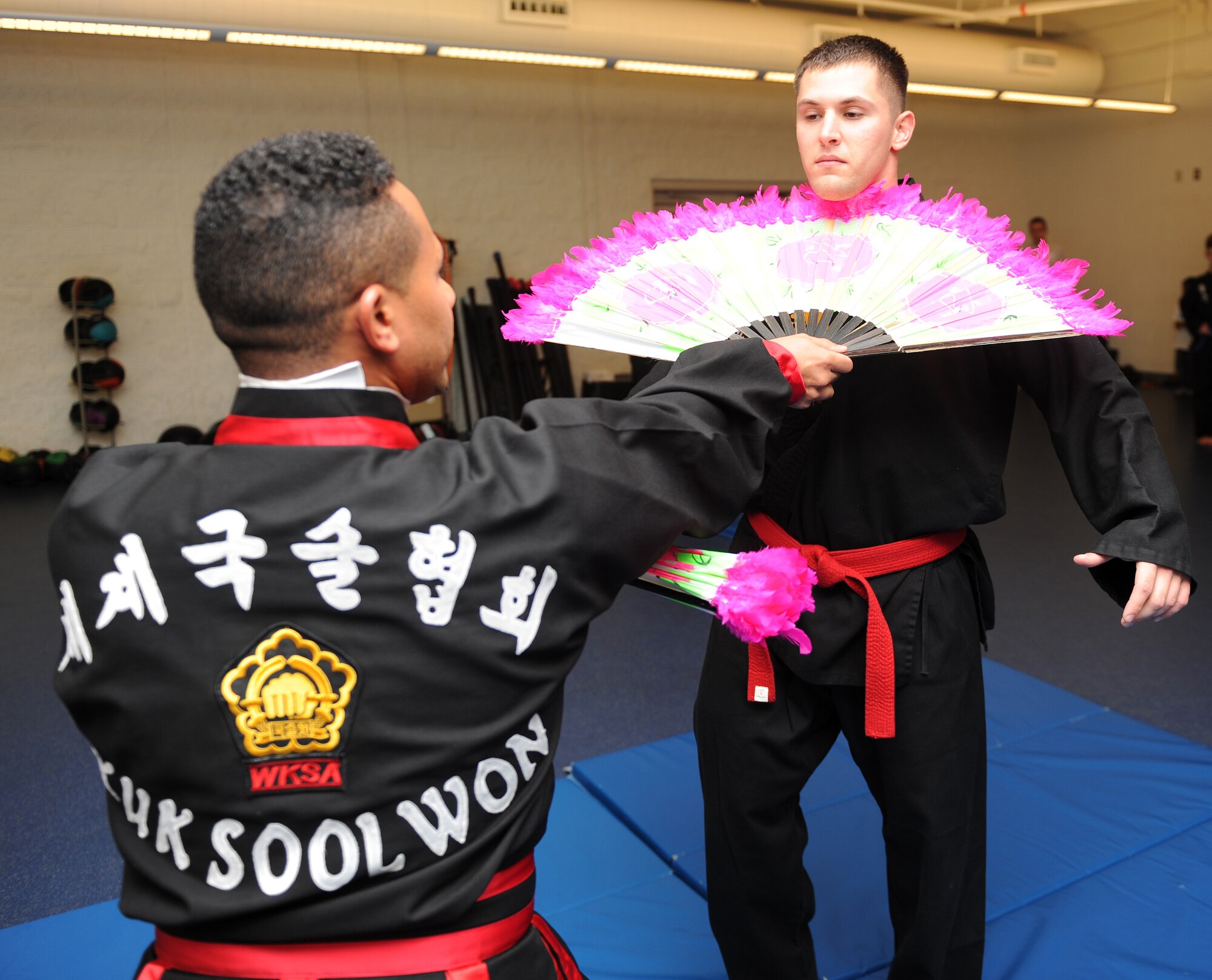 Retired Master Sgt. Amado Garcia, who was previously assigned to the 96th Aircraft Maintenance Squadron, Eglin Air Force Base, Fla., holds a student at bay with a fan during a Kuk Sool Won class at the Aderholt Gym on Hurlburt Field, Fla., Dec. 2, 2013. The fan is one of more than 20 traditional weapons used in Kuk Sool Won. (U.S. Air Force photo/Senior Airman Kentavist P. Brackin) 