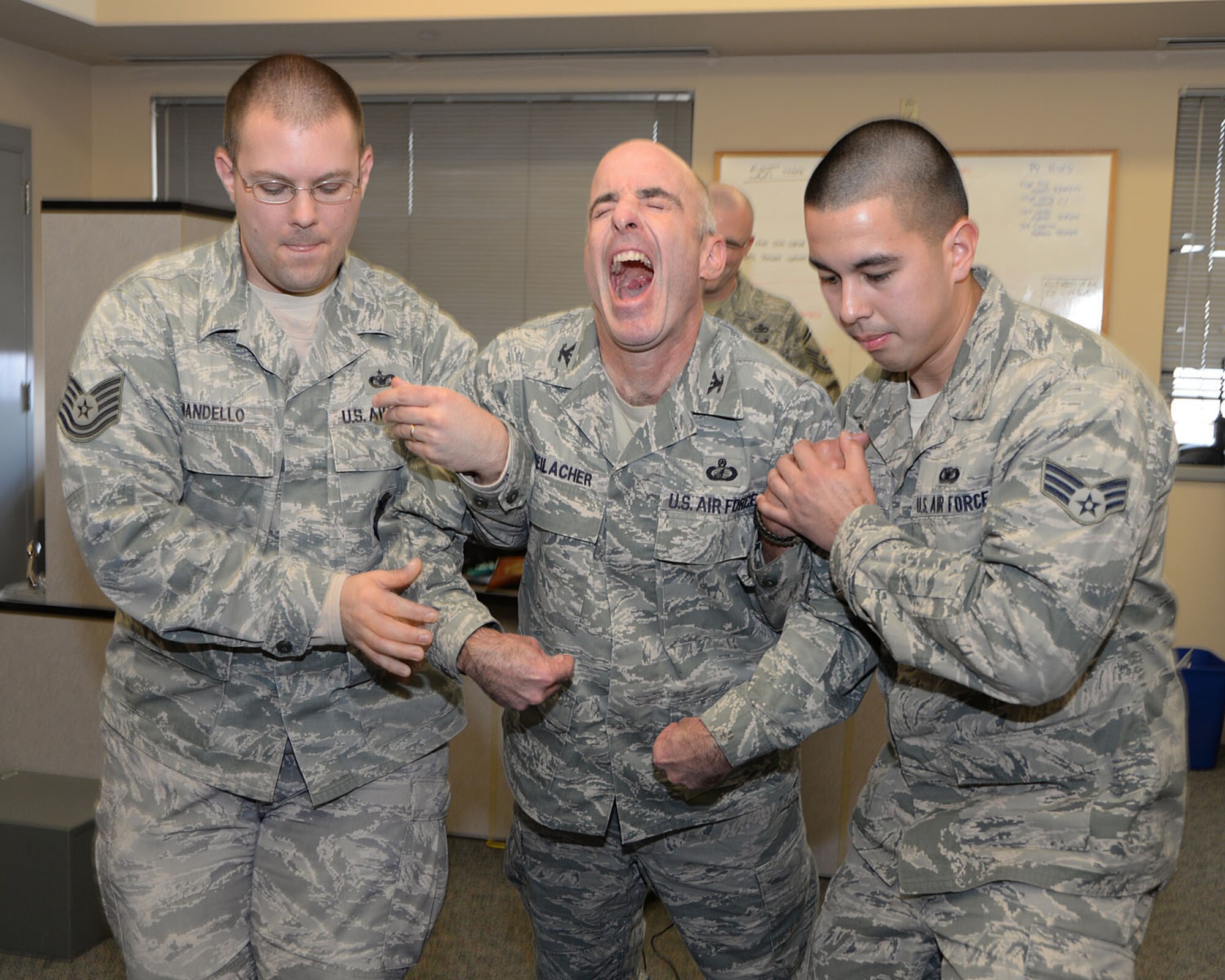 Tech. Sgt. Michael Mandello (left) and Senior Airman Jeremy Caparaz, both assigned to the 66th Security Forces Squadron, hold up Col. Lester A. Weilacher, 66th Air Base Group commander, as he is tased by Senior Master Sgt. Joseph Barden as part of a Taser demonstration during 66 SFS augmentee training Dec. 20. (U.S. Air Force photo by Mark Herlihy)