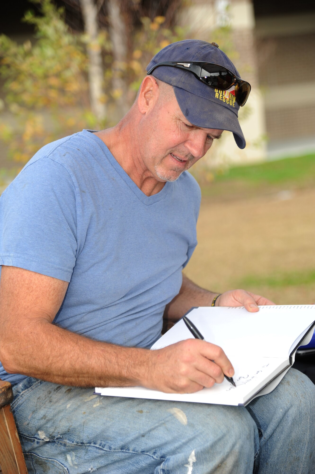 Marlin Miller, Florida sculptor, autographs his book for Brig. Gen. Patrick Higby, 81st Training Wing commander, Dec. 20, 2013, in front of the exchange, at Keesler Air Force Base, Miss.  Miller has sculpted dozens of wooden figures from Hurricane Katrina-battered trees along the Gulf Coast, including the eagle in front of the exchange.  (U.S. Air Force photo by Kemberly Groue)