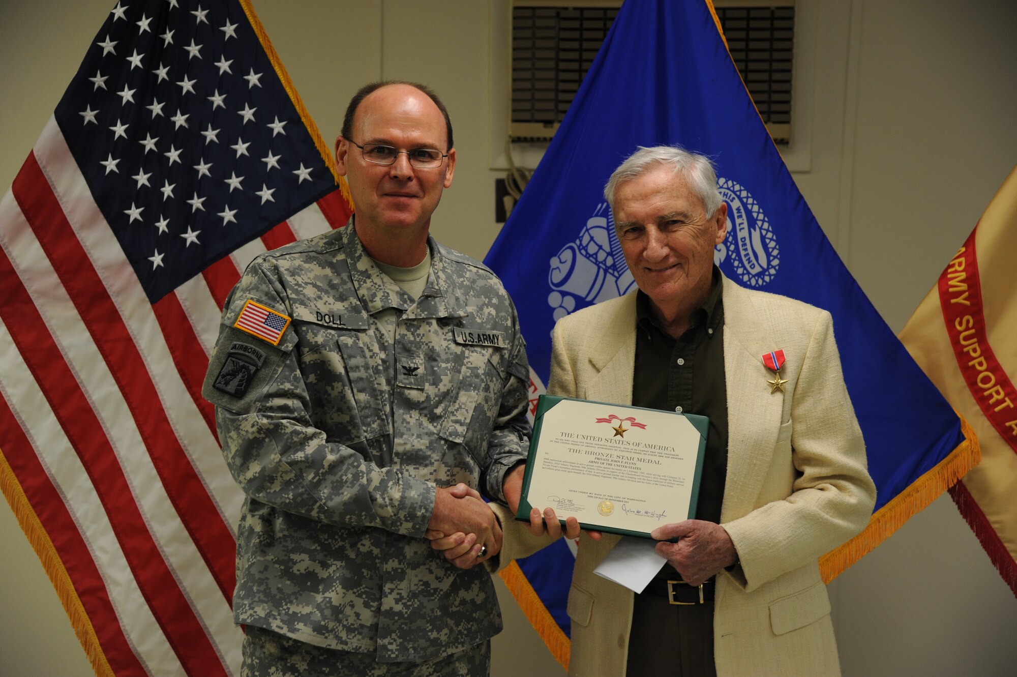 Army Col. Jeffery Doll, Army Support Activity-Fort Dix commander, presents the Bronze Star medal to John F. Flynn, World War II-era Army sergeant, Dec. 17, 2013, in the U.S. Army Reserve Mobilization Museum at Joint Base McGuire-Dix-Lakehurst, N.J. Flynn’s unit was the first to advance the Rhine River and spent most of the time in trenches and foxholes. (U.S. Air Force photo by Airman 1st Class Sean M. Crowe/Released)