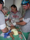 Maj. Mitch Reynolds (right), an Air Force reservist in the 419th Medical Squadron, treats a baby with third-degree burns on his hand in the Philippines last month. Team Rubicon, a nonprofit organization, works to send military veterans to the sites of natural disasters so their skills can be put to use. Reynolds is a certified registered nurse anesthetist in his civilian career. (Courtesy photo)