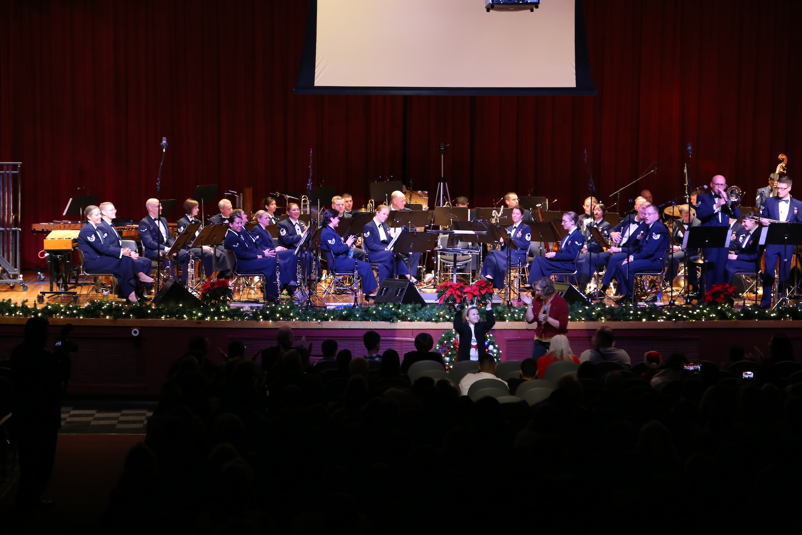 Air Force Master Sgt. Nancy Poffenbarger, Air Force Band of the West vocalist, chooses children from the audience to accompany her while she sings a variety of holiday songs Dec. 17 at the Joint Base San Antonio-Lackland Bob Hope Theater. (U.S. Air Force photo by Airman 1st Class Lincoln Korver)