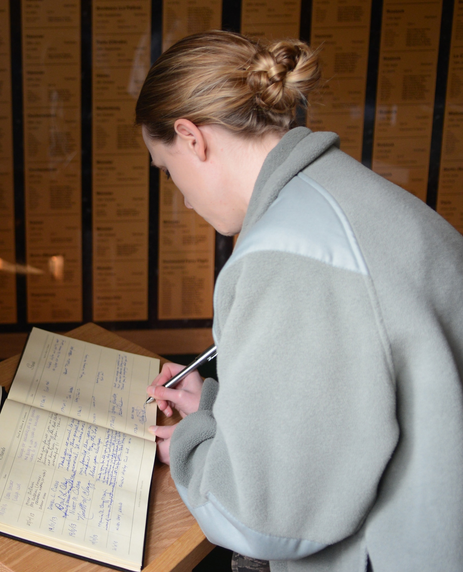 U.S. Air Force 2nd Lt. Kelsey Tarver, 100th Air Refueling Wing protocol officer, signs a guest book Dec. 17, 2013, during a heritage visit to the 95th Bombardment Group Heritage Association at RAF Horham, Norfolk, England. During the heritage trip, Team Mildenhall leadership and museum volunteers taught Airmen about the rich history of U.S. military presence in the U.K. (U.S. Air Force photo by Airman 1st Class Dillon Johnston/Released)