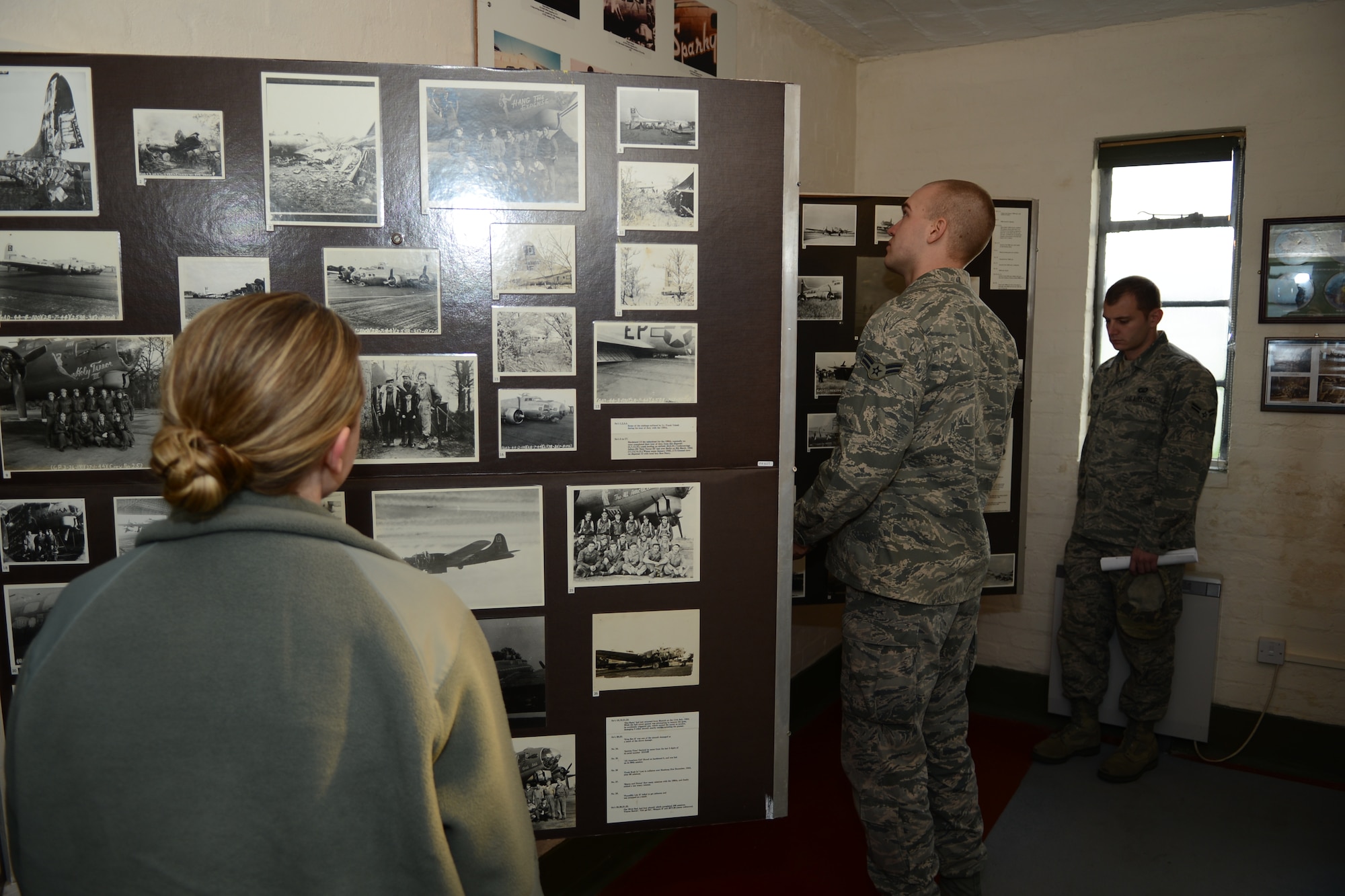 Team Mildenhall members examine photos from World War II Dec. 17, 2013, during a heritage visit to the 100th Bombardment Group Memorial Museum at RAF Thorpe Abotts, Norfolk, England. During the heritage trip, Team Mildenhall leadership and museum volunteers taught Airmen about the rich history of U.S. military presence in the U.K. (U.S. Air Force photo by Airman 1st Class Dillon Johnston/Released)