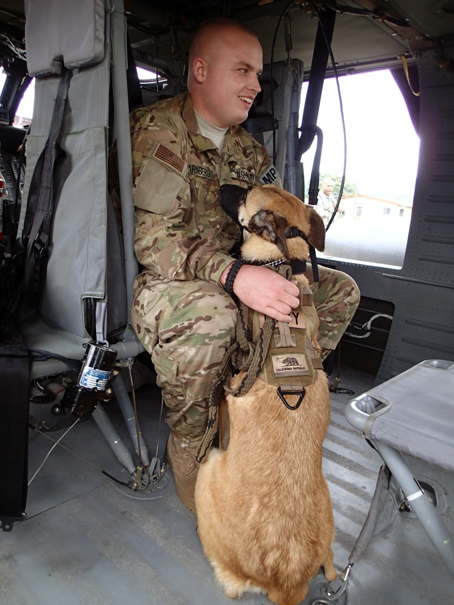 U.S. Navy Master at Arms Petty Officer 3rd Class Ryan Jarnberg, a military working dog handler assigned to Joint Task Force-Bravo's Joint Security Forces (JSF), sits in the cabin of a UH-60 Blackhawk helicopter with his dog during a medical evacuation (MEDEVAC) familiarization exercise at Soto Cano Air Base, Honduras, Dec. 19, 2013.  Joint Task Force-Bravo’s Medical Element (MEDEL) teamed up with the 1- 228th Aviation Regiment and JSF to conduct the exercise to familiarize the dogs and their handlers in MEDEVAC procedures in case the dogs ever require an emergency medical evacuation. (Photo by U.S. Army Sgt. Jennifer Shick)