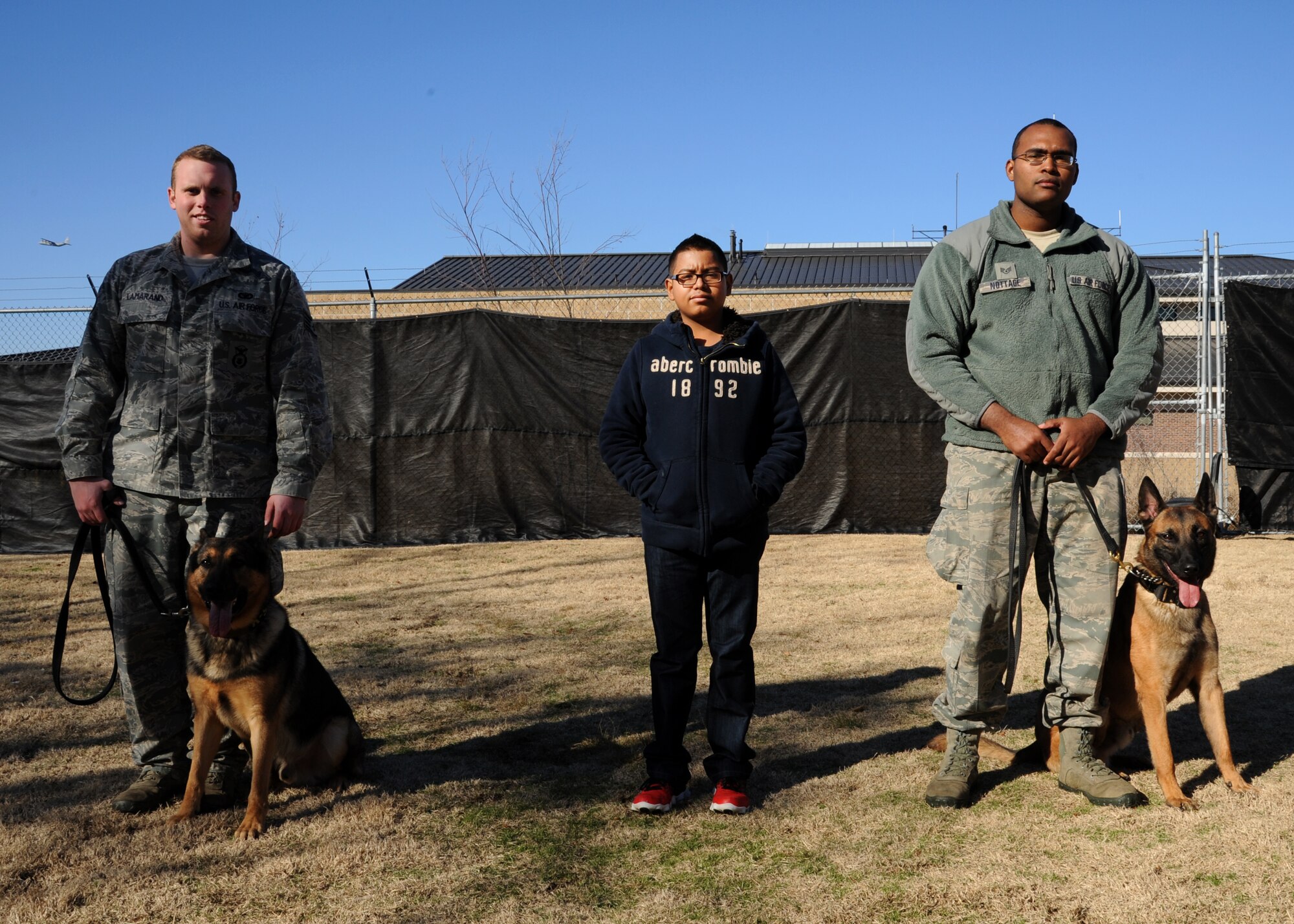 Alejo Resendiz stands between two military police dogs and their handlers Dec 13, 2013, at Little Rock Air Force Base, Ark. Alejo toured the 19th Security Forces Squadron kennels as part of his wish to become “pilot for a day” at The Rock, through the Make-A-Wish® program (U.S. Air Force photo by Airman 1st Class Harry Brexel)
