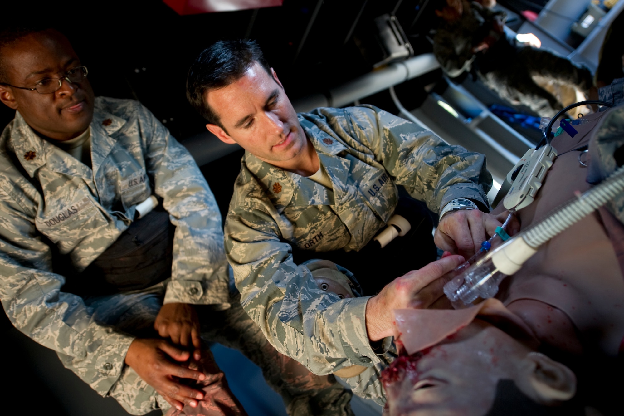 Maj. Geoffrey Douglas, Air Force Special Operations Command general surgeon and Maj. Reid Orth, AFSOC emergency room physician, practice treating a critically wounded patient in a simulated aircraft on Hurlburt Field, Fla., Dec. 18, 2013.  The training is part of the AFSOC Casualty Evacuation course, which prepares medical teams for deployments. (U.S Air Force photo/Senior Airman Naomi Griego)