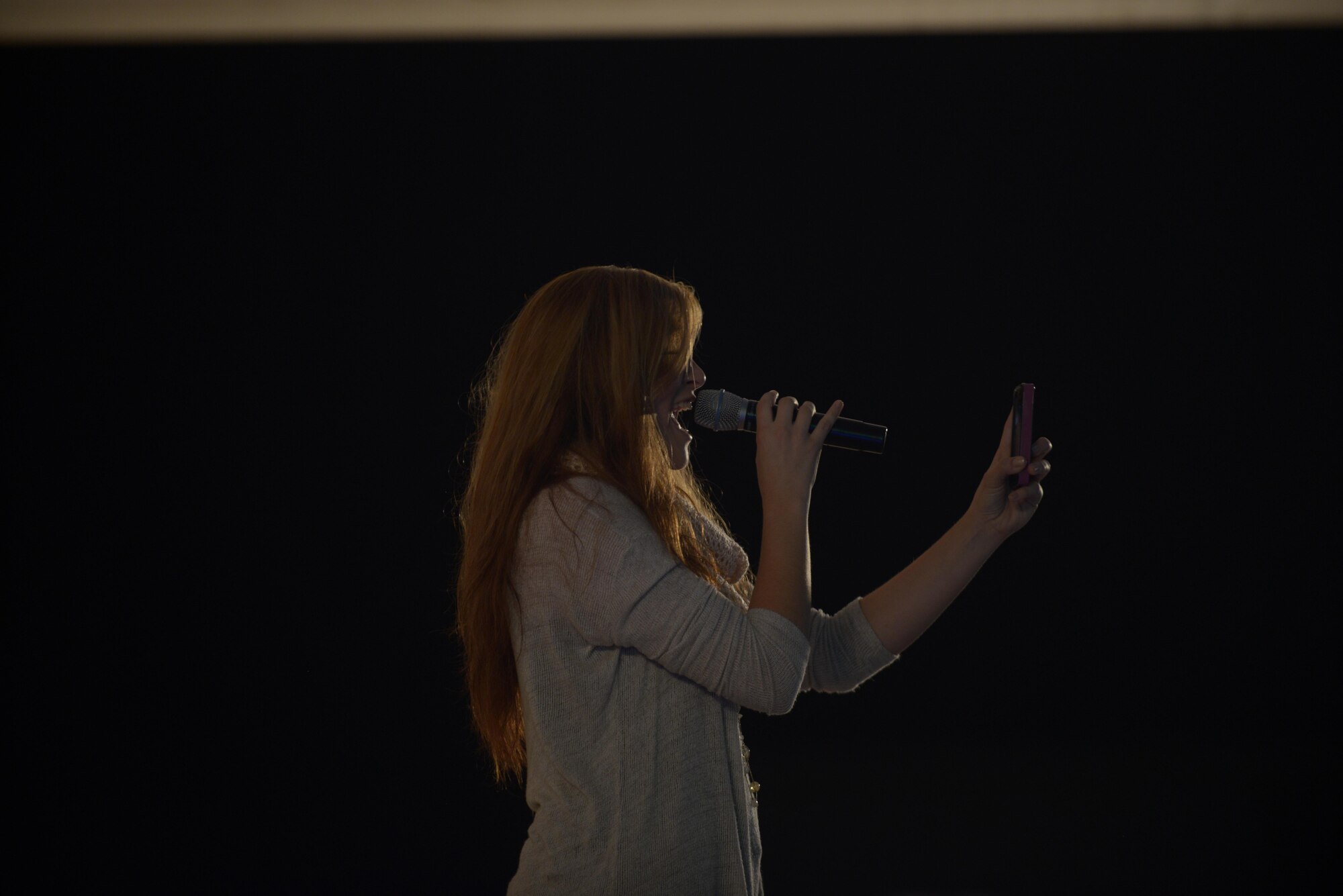 Alaina Blair, a country music artist, takes a crowd photo during her performance for service members at the 379th Air Expeditionary Wing in Southwest Asia, Dec. 19, 2013.  Blair, along with her band, performed 11 concerts in five countries across the U.S. Air Forces Central Command area of responsibility over an 18 day period. Completing the Armed Forces Entertainment tour here, Blair sang a mix of her own music, cover songs and Christmas carols to the audience, providing an interactive performance while spreading holiday cheer. (U.S. Air Force photo by Master Sgt. David Miller)
