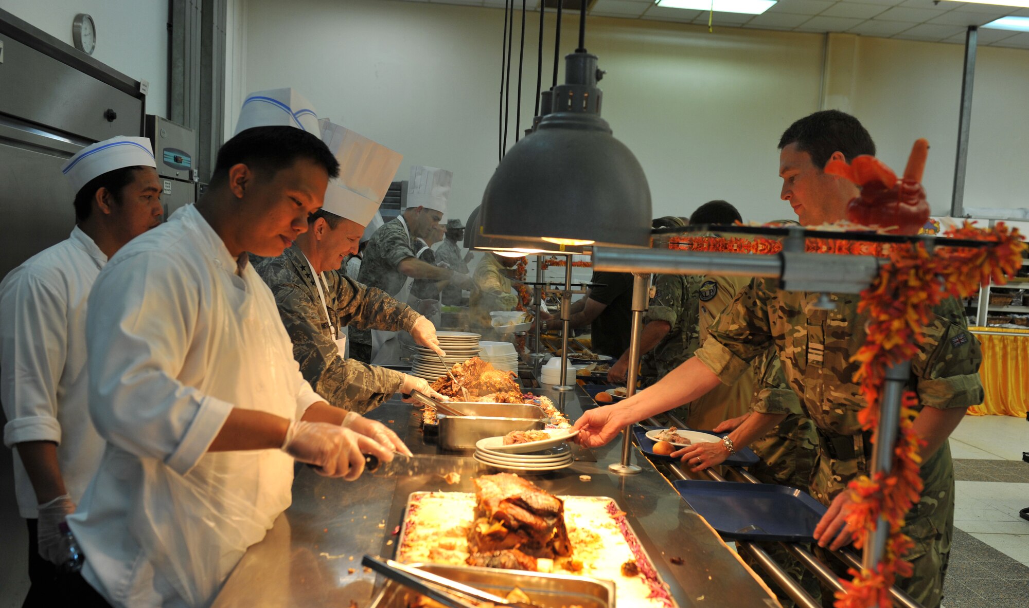 Other country nationals team up with senior leadership to serve Thanksgiving Day meals to deployed members assigned to the 379th Air Expeditionary Wing and coalition partners in Southwest Asia, on Nov. 28, 2013. Other country nationals work on a daily basis with the 379th Force Support Squadron food services to prepare and serve meals 24/7. (U.S. Air Force photo/Master Sgt. David Miller)
