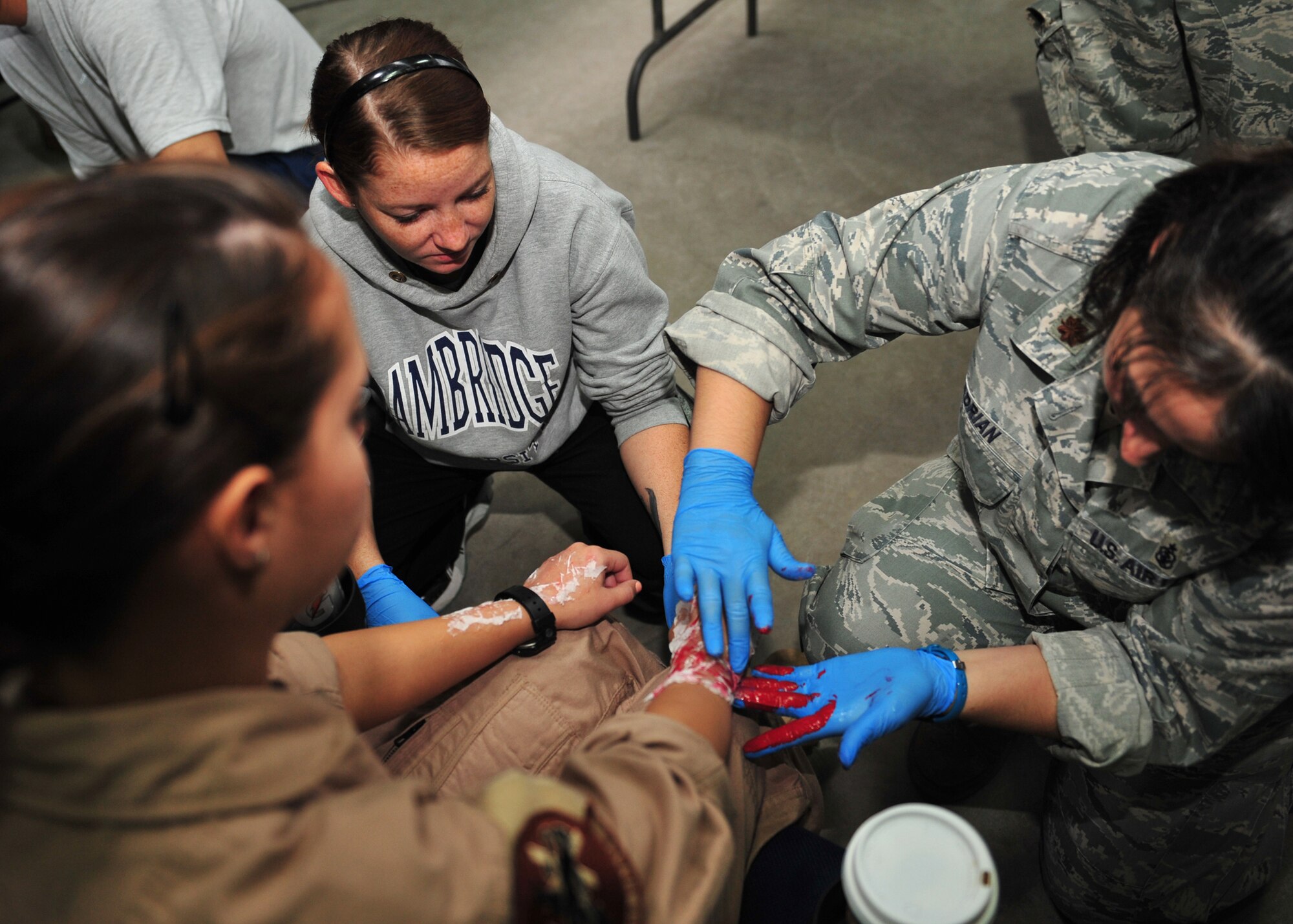 Air Force Staff Sgt. Samantha and Air Force Maj. Dana Adrian, who are both assigned to the 380th Expeditionary Medical Group moulage team, apply make-up to Air Force Airman 1st Class Jenna Kester, an airborne radar technician assigned to the 968th Expeditionary Airborne Air Control Squadron, to simulate burns at an undisclosed location in Southwest Asia, Dec. 19, 2013. (U.S. Air Force photo by Staff Sgt. Michael Means/Released)