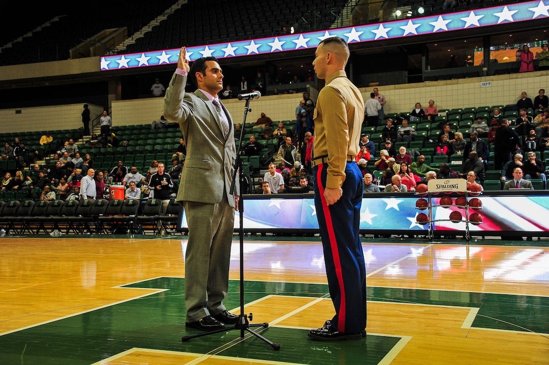U.S. Marine Corps Capt. Nathan Harmon, Recruiting Station Detroit’s Officer Selection Officer, administers the oath of enlistment to Shane Azizi during half time at Eastern Michigan University men's basketball game against the University of Massachusetts Dec. 3, 2013. Azizi was one of 38 individuals selected for a reserve contract, and he is slated to attend Officer Candidates School January 2014. (U.S. Marine Corps photo by Sgt. Elyssa Quesada/Released)