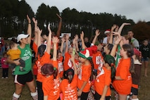 Girls from Delalio Elementary School aboard Marine Corps Air Station New River give their group cheer at the semi-annual Girls on the Run celebration, Dec. 7. The group, led by Marines from Marine Corps Aviation Logistics Squadron 29, participated in the 5k as part of the programs cirriculum of promoting self-awareness through physical fitness.