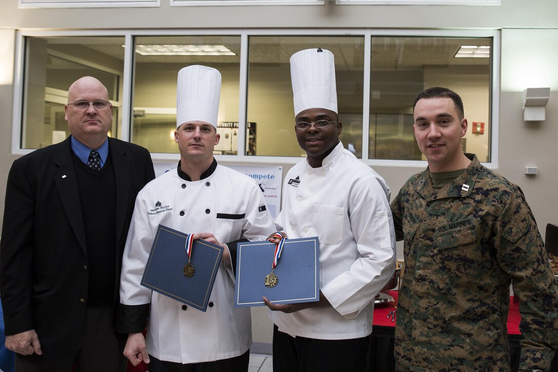 Sgt. Matthew Phillips(middle left), food service Marine at Marine Barracks Washington, D.C., and Cpl. Dominic Richburg(middle right), food service Marine at the Barracks, are presented 1st place during the Culinary Team of the Quarter Competition at the Barracks, Dec. 17. The event pitted the food service Marines against the civilian workers in a cookoff. (Official Marine Corps photo by Lance Cpl. Dan Hosack/Released)