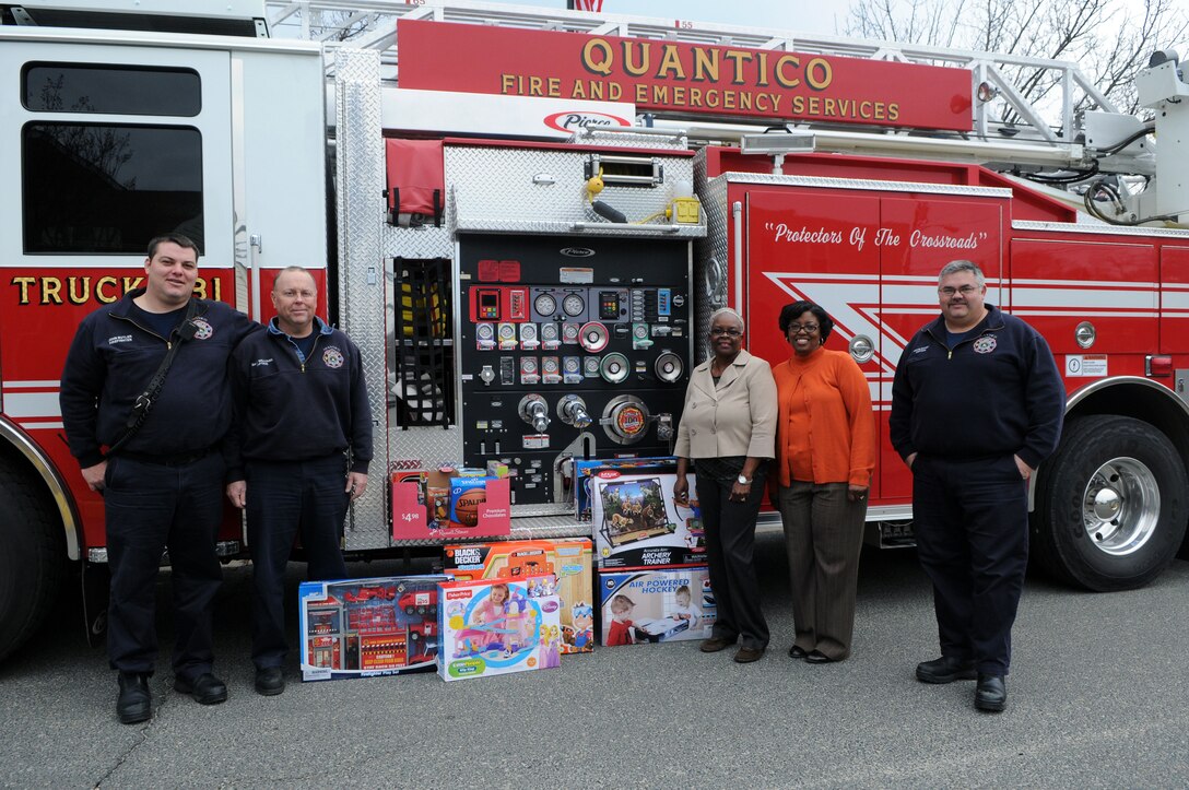 From left, Firefighter John Butler, Capt. David Williams, town Treasurer Debra Kidwell, town Clerk Rita Frazier and Capt. Kevin Dickey show the toys that Marine Corps Base Quantico firefighters will bring from the Quantico town office to the Toys for Tots warehouse Dec. 17, 2013.