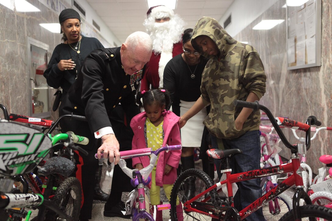 NEW ORLEANS – Lt. Gen. Richard P. Mills, commander of Marine Forces Reserve and Marine Forces North encourages a child to take her new bicycle for a ride during a U.S. Marine Corps Reserve Toys for Tots event at the New Orleans City Hall, Dec. 21, 2013. During this event, the Marines teamed up with the Zulu Social Aid and Pleasure Club to distribute more than 1,000 toys and bicycles to disadvantaged families. (Official photo by Sgt. Fenton Reese)