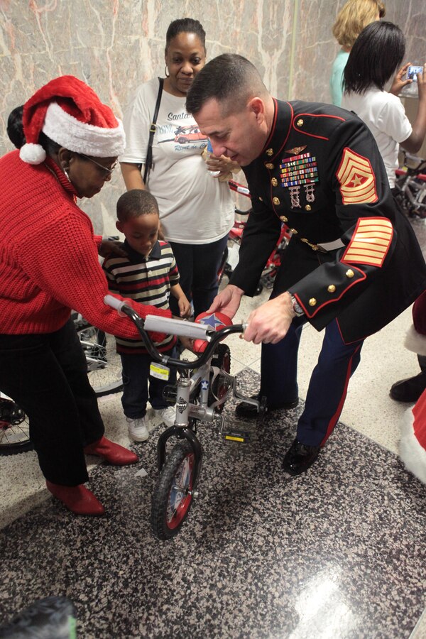 NEW ORLEANS – Sgt. Maj. Anthony A. Spadaro, Marine Forces Reserve and Marine Forces North sergeant major, presents a child with a new bicycle at the New Orleans City Hall during a U.S. Marine Corps Reserve Toys for Tots event, Dec. 21, 2013. During this event, the Marines teamed up with the Zulu Social Aid and Pleasure Club to distribute more than 1,000 toys and bicycles to disadvantaged families. (Official photo by Sgt. Fenton Reese)