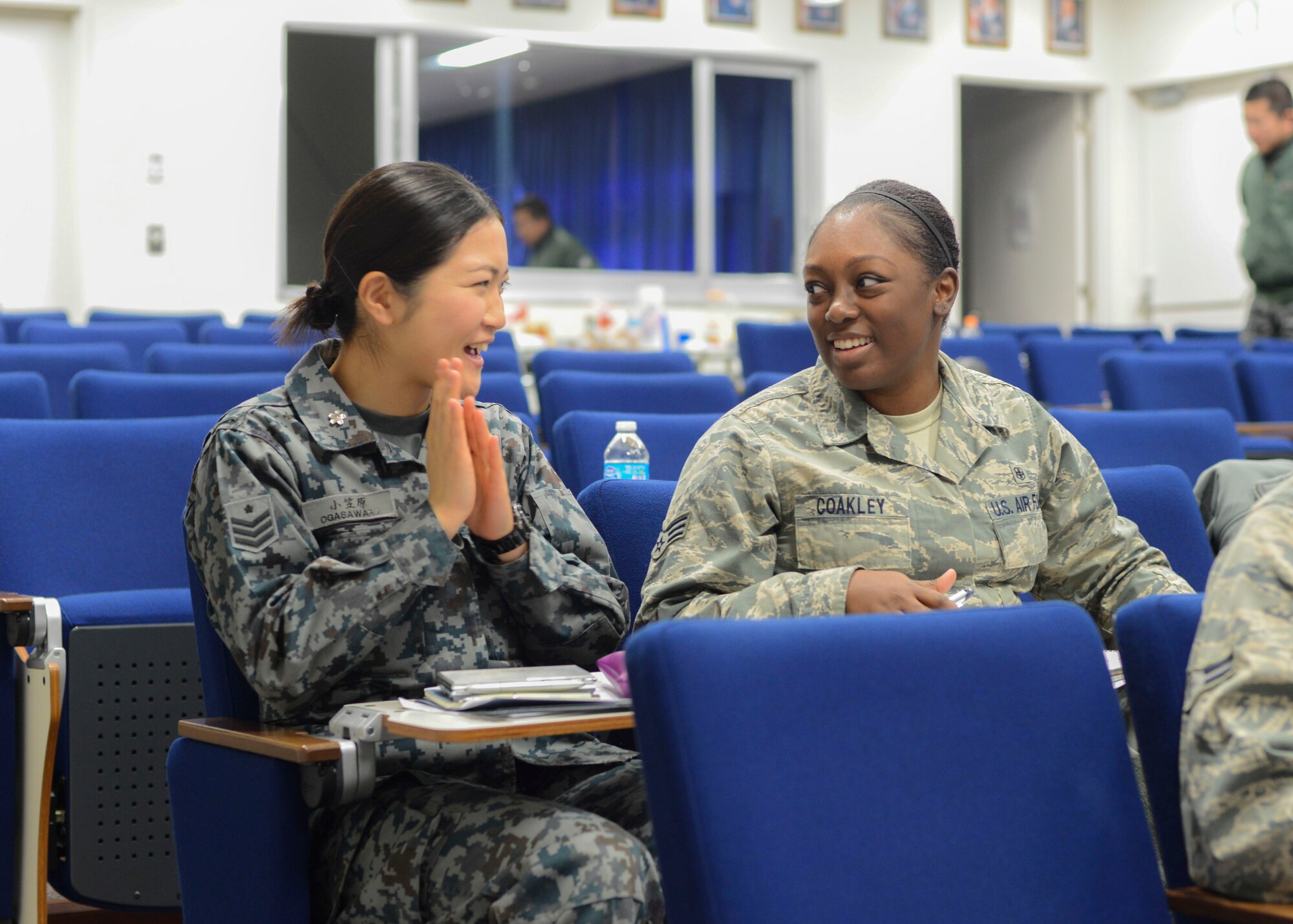 Senior Airman Satomi Ogasawara and SrA. Chuntay Coakley, students attending the bilateral Airman Professional Enhancement Seminar, shares a conversation during break at Yokota Air Base, Japan, Dec. 17, 2013.  The seminar taught both American and Japanese service members leadership and how to be successful.  (U.S. Air Force photo by Airman 1st Class Soo C. Kim / Released)