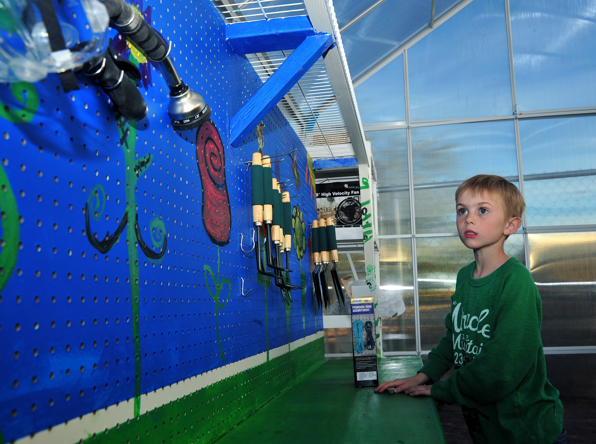 A child from the School Age Program looks at gardening tools at Davis-Monthan Air Force Base, Ariz., Dec. 17, 2013. These tools allowed children to help dig, plant and water plants in the greenhouse, which teaches the children the process of growing various types of seeds. (U.S. Air Force photo by Airman 1st Class Betty R. Chevalier/Released)