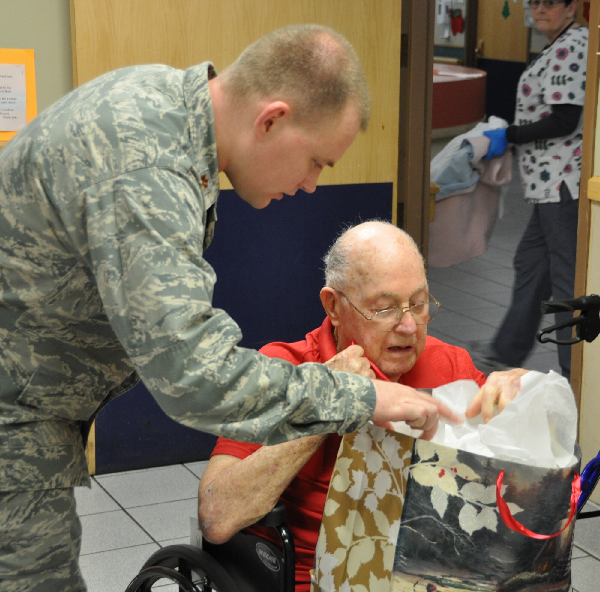 Major Jon Quinlan, 507th Air Refueling Wing helps a veteran open a Christmas present at the Annual Norman Veterans Center Christmas party, Dec. 23.  (U.S. Air Force Photo/Senior Airman Mark Hybers)