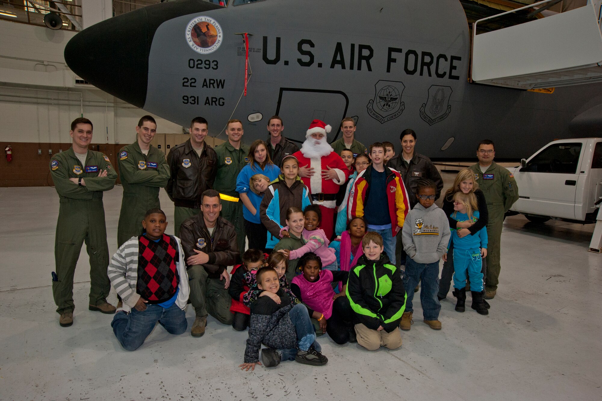 Airmen from the 349th Air Refueing Squadron pose with children from Big Brothers Big Sisters Wichita Dec. 20, 2013, at McConnell Air Force Base, Kan. The children were given a tour of the base that ended with a surprise visit from "Santa" that included many of the gifts on their wish lists. (U.S. Air Force photo/Airman 1st Class Victor J. Caputo)