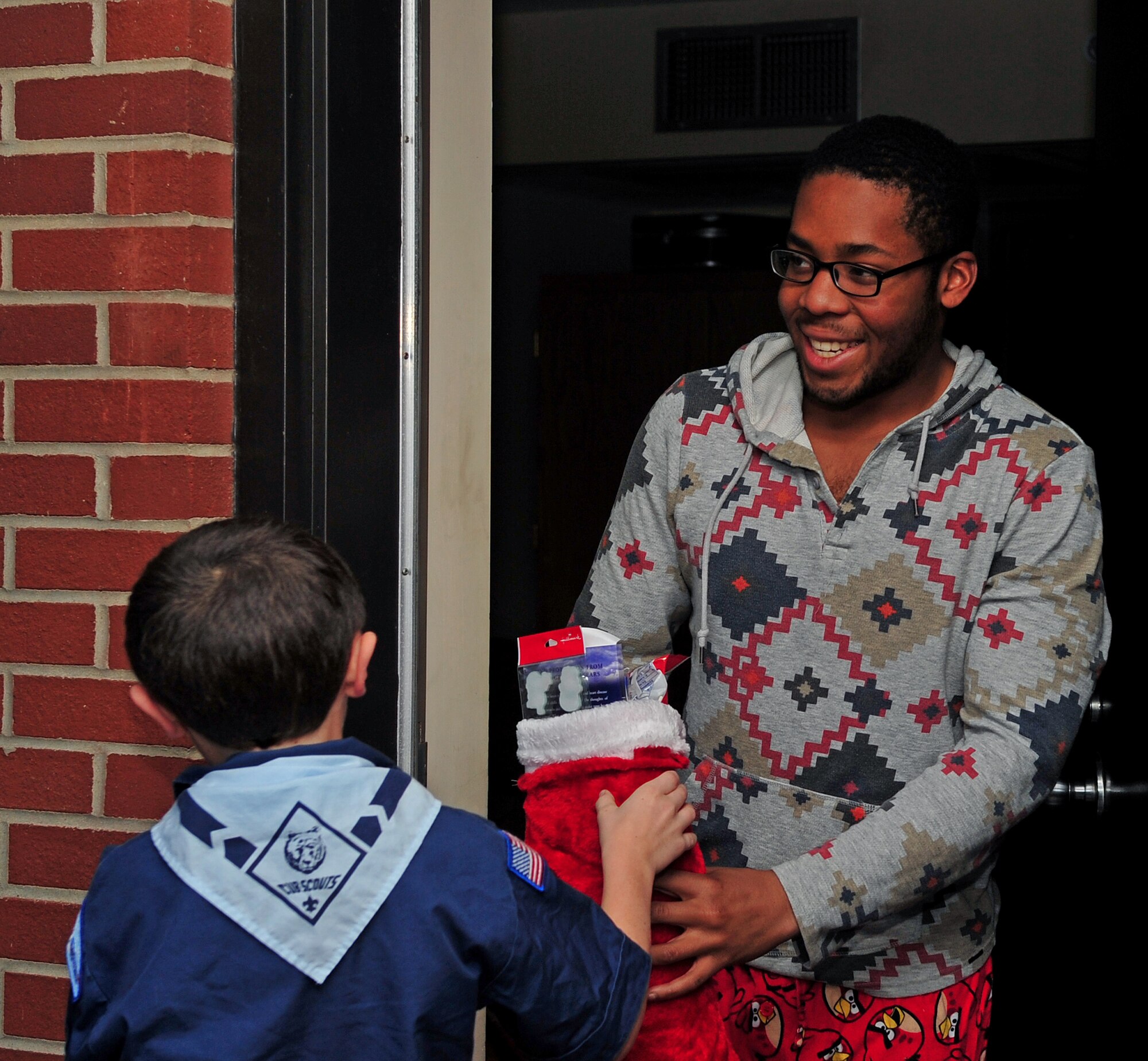 Airman 1st Class Khari Manning, 4th Equipment Maintenance Squadron aircraft structural maintainer, receives his stocking from the son of Staff Sgt. Christopher Love, left, 4th Operations Support Squadron aircrew flight equipment craftsman, at Seymour Johnson Air Force Base, N.C., Dec. 19, 2013. Manning was one of 110 Airmen to receive a stocking from the base chapel. (U.S. Air Force photo by Airman 1st Class Shawna Keyes)