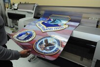 A graphics designer laminates a poster Dec. 12 at Joint Base San Antonio-Randolph. Office hours for the graphics department at all three locations are 7 a.m. to 4 p.m. Monday through Friday. (U.S. Air Force photo by Richard McFadden) 