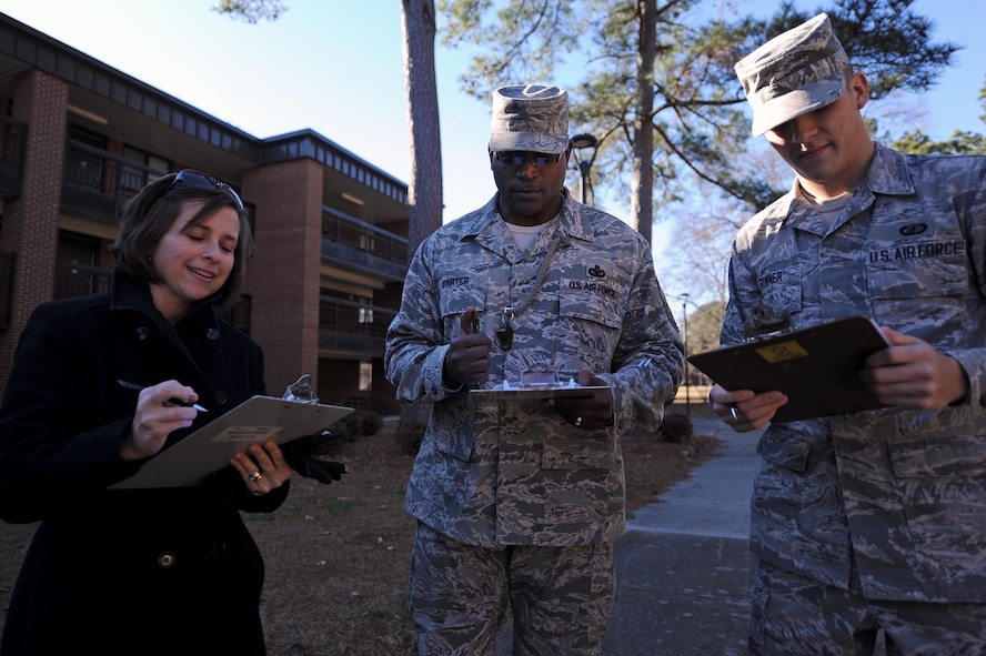 From left, Kirsten Pettus, wife of Col. Lamar Pettus, 4th Fighter Wing vice commander, Chief Master Sgt. Woodrow Carter, 4th Mission Support Group superintendent, and Airman 1st Class Devin Powner, 4th Contracting Squadron contract specialist, compare notes from the dorm room door decoration contest at Seymour Johnson Air Force Base, N.C., Dec. 18, 2013. Doors were judged on creativity and originality with prizes going to the top three contestants. (U.S. Air Force photo by Airman 1st Class Aaron J. Jenne)