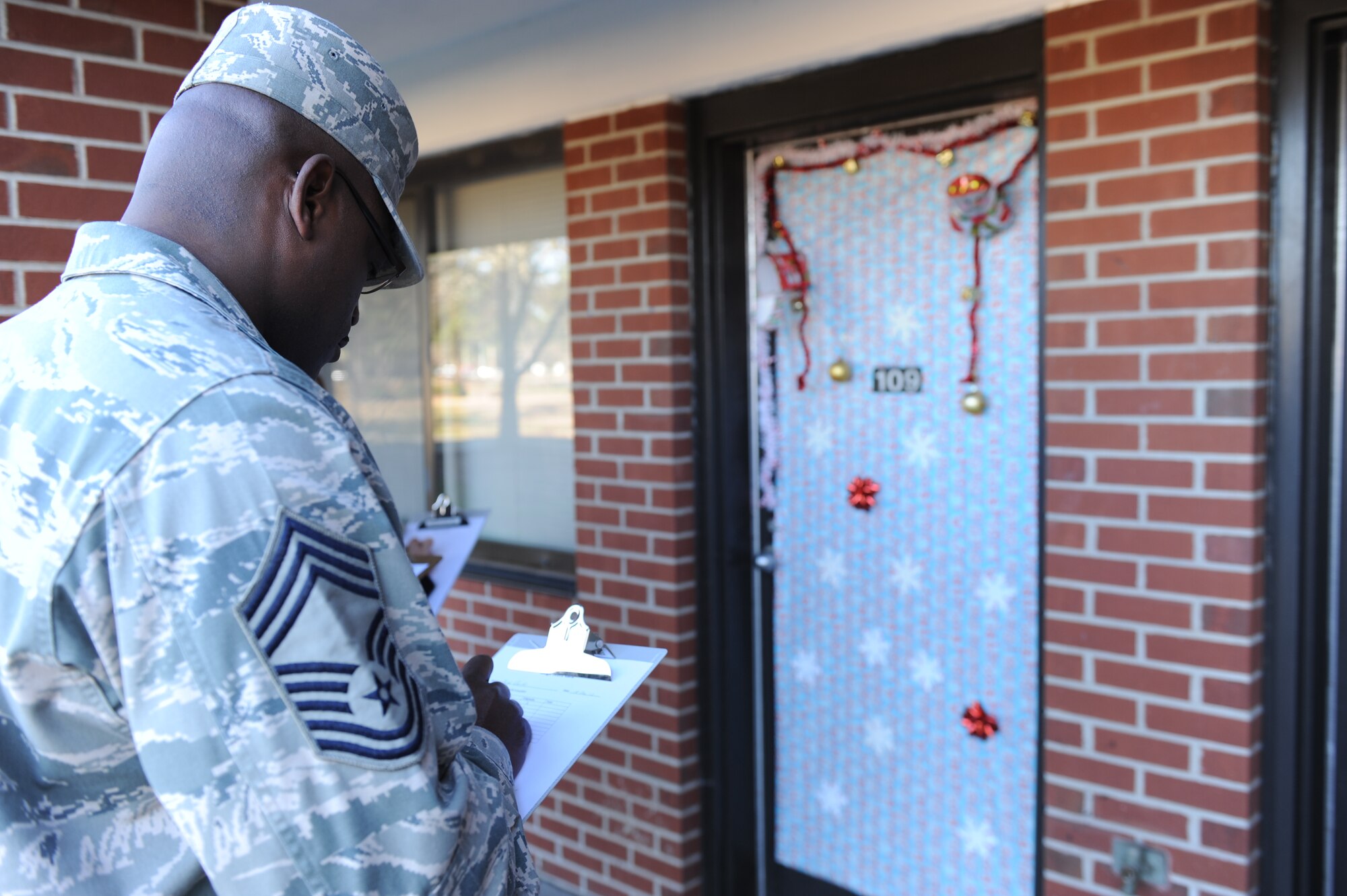 Chief Master Sgt. Woodrow Carter, 4th Mission Support Group superintendent, judges a contestant’s entry during a dorm room door decoration contest at Seymour Johnson Air Force Base, N.C., Dec. 18, 2013. The contest was open to all dorm residents for a chance to win prizes such as movie tickets and gift certificates. (U.S. Air Force photo by Airman 1st Class Aaron J. Jenne)