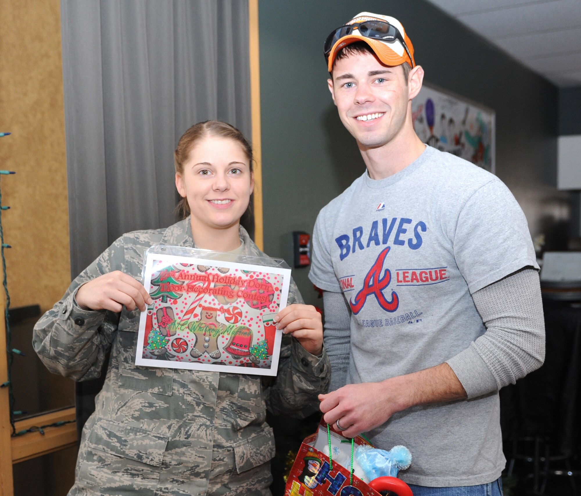 Airman 1st Class Whitney Mullins, 341st Medical Support Squadron family health administrative technician (left), receives an award from Staff Sgt. Kenneth Shelton, 341st Civil Engineer Squadron Airmen dorm leader, for being the runner-up in the second annual dorm decorating contest during a pizza party at the Malmstrom Air Force Base Detour on Dec. 20.  The Consolidated Dorm Management Office sponsored the event. (U.S. Air Force photo/Senior Airman Katrina Heikkinen)