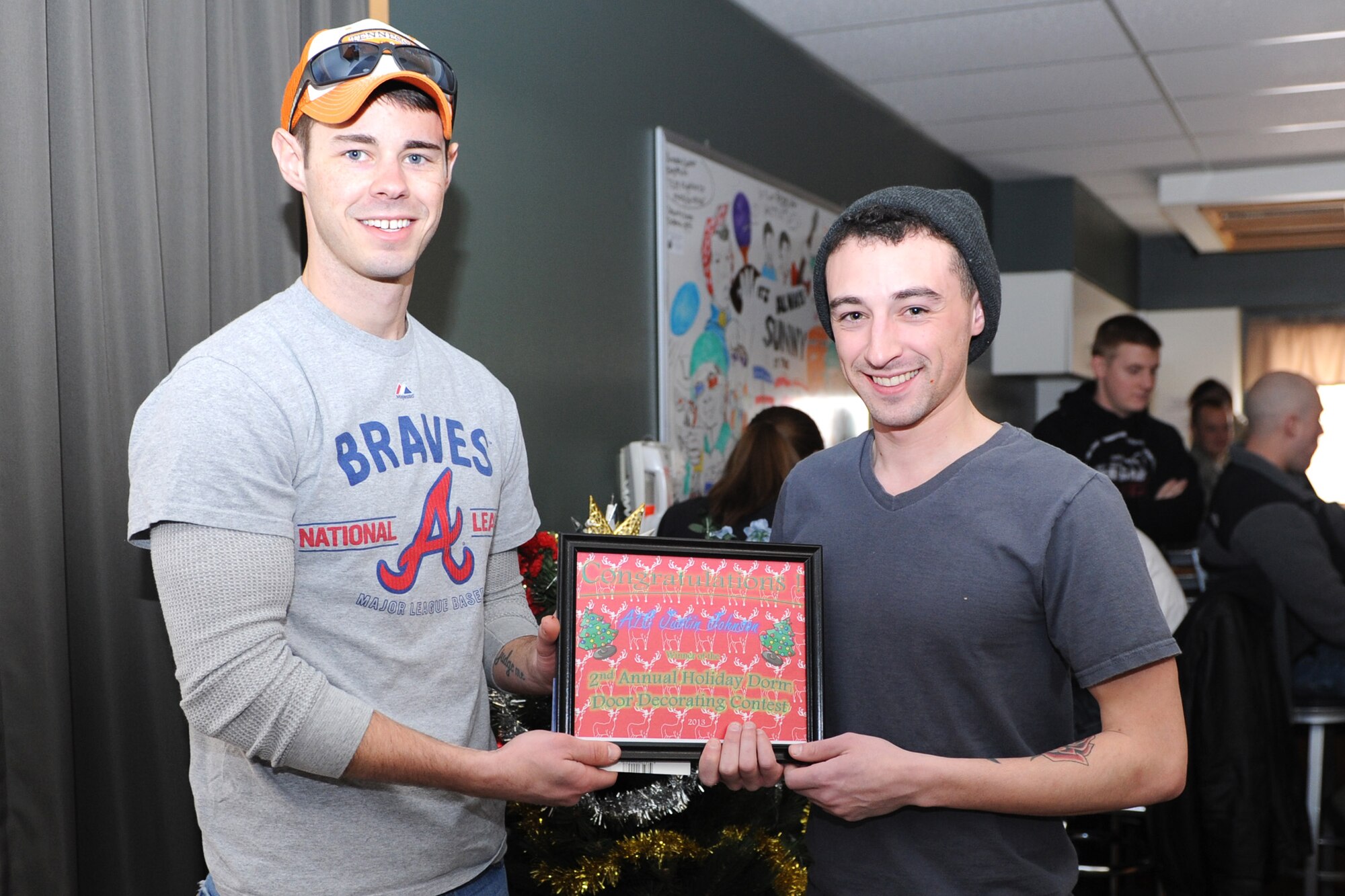 Airman 1st Class Justin Johnson, 341st Missile Security Forces Squadron member (right), receives an award from Staff Sgt. Kenneth Shelton, 341st Civil Engineer Squadron Airmen dorm leader, for winning the second annual holiday dorm decorating contest during a pizza party at the Detour on Dec. 20.  Six Airmen participated in the contest, which was sponsored by the Consolidated Dorm Management Office. (U.S. Air Force photo/Senior Airman Katrina Heikkinen)